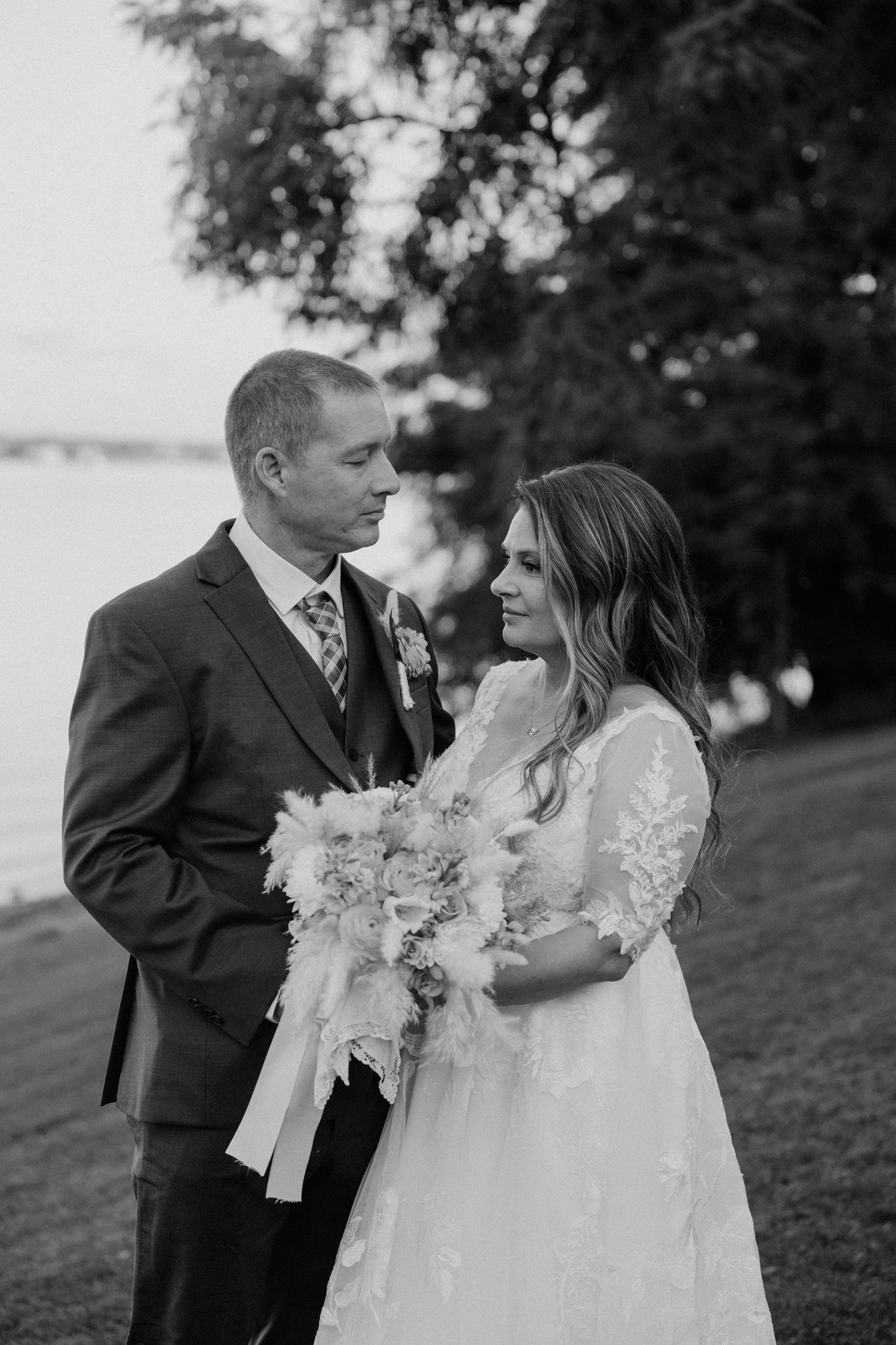A romantic black and white photo of a bride and groom sharing intimate moments outdoors.