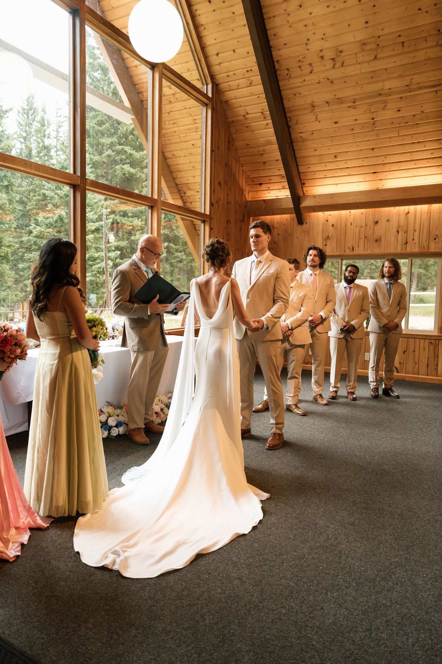 Bride and groom exchanging vows at altar in rustic wooden chapel with groomsmen.