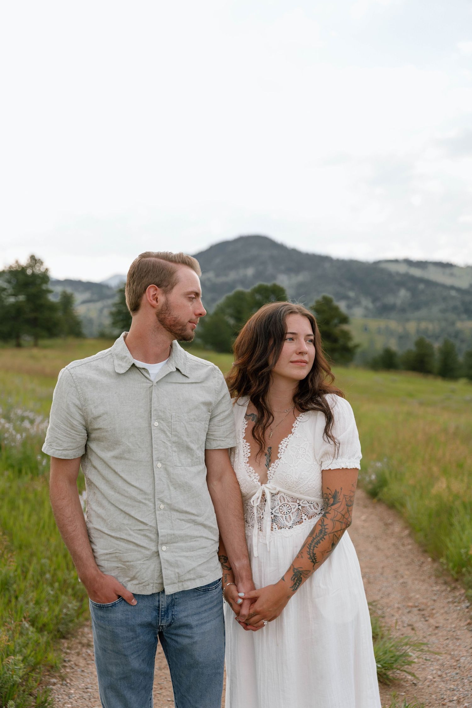 Couple in casual attire holding hands on mountain trail.