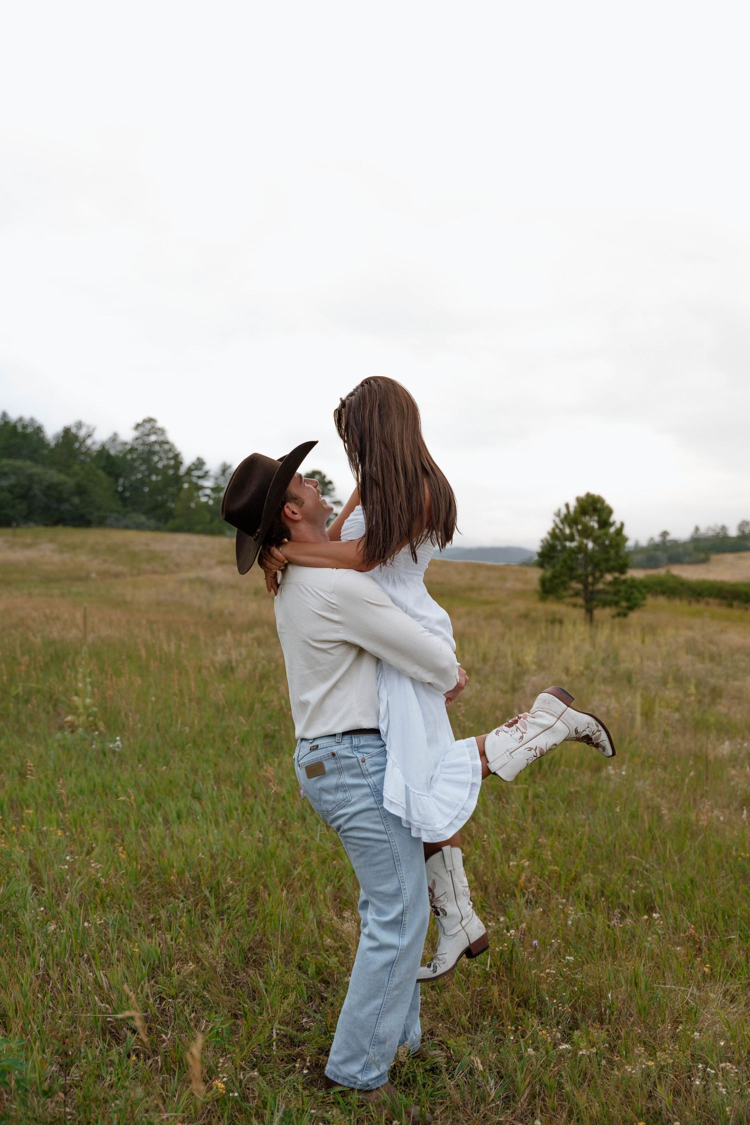 A joyful couple embraces while spinning in a wildflower field.
