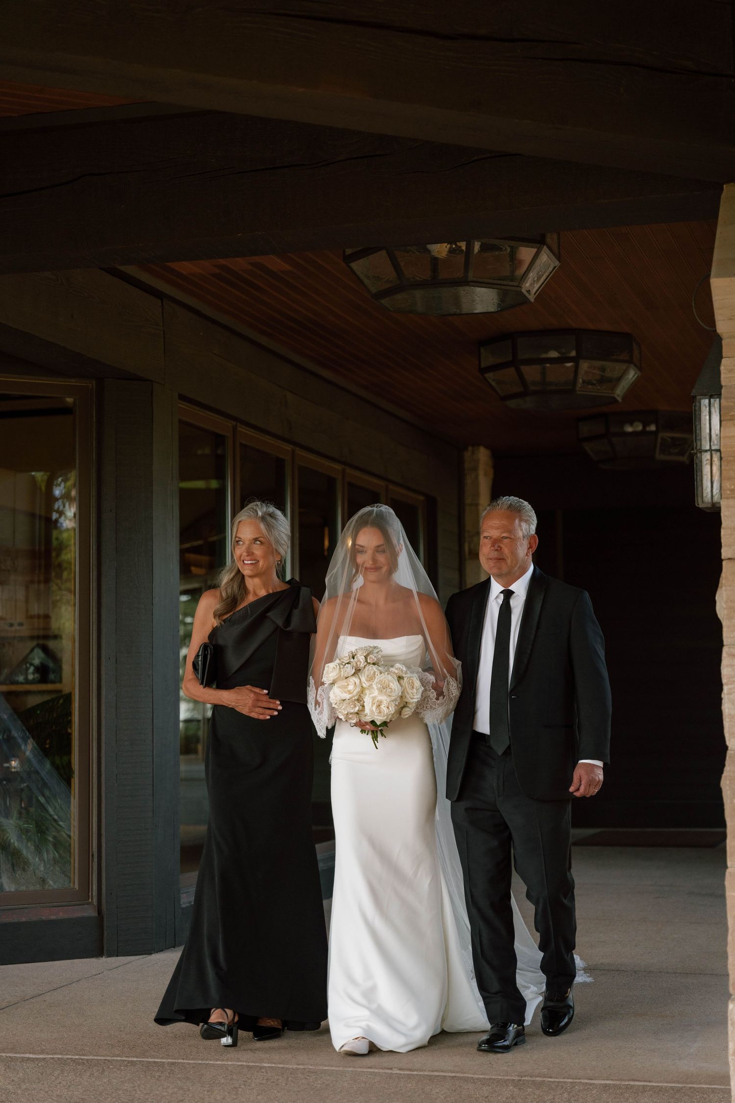 Wedding party walking through a covered walkway at an elegant stone venue.