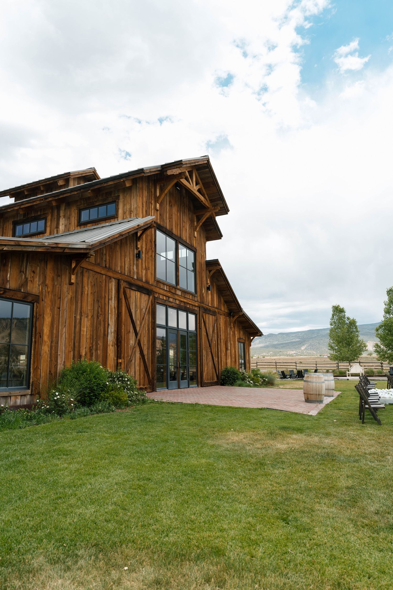 Rustic wooden barn wedding venue with large windows set against mountain landscape.