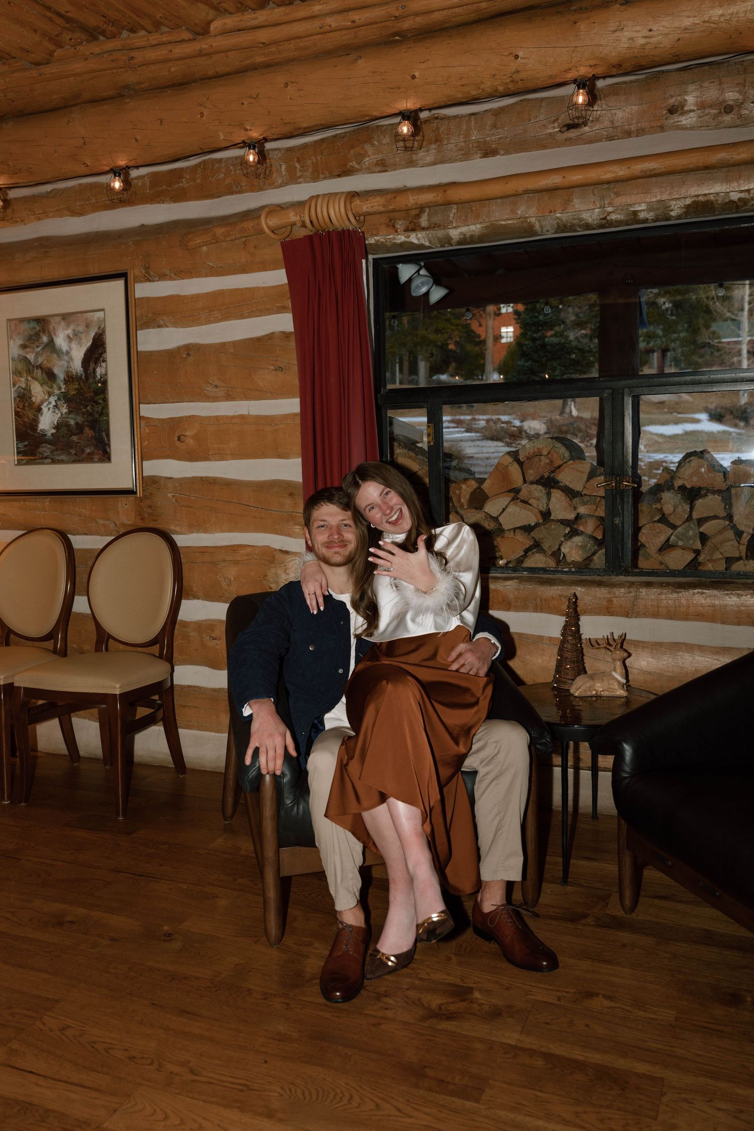 Couple relaxing in rustic log cabin interior with wooden walls and floors.