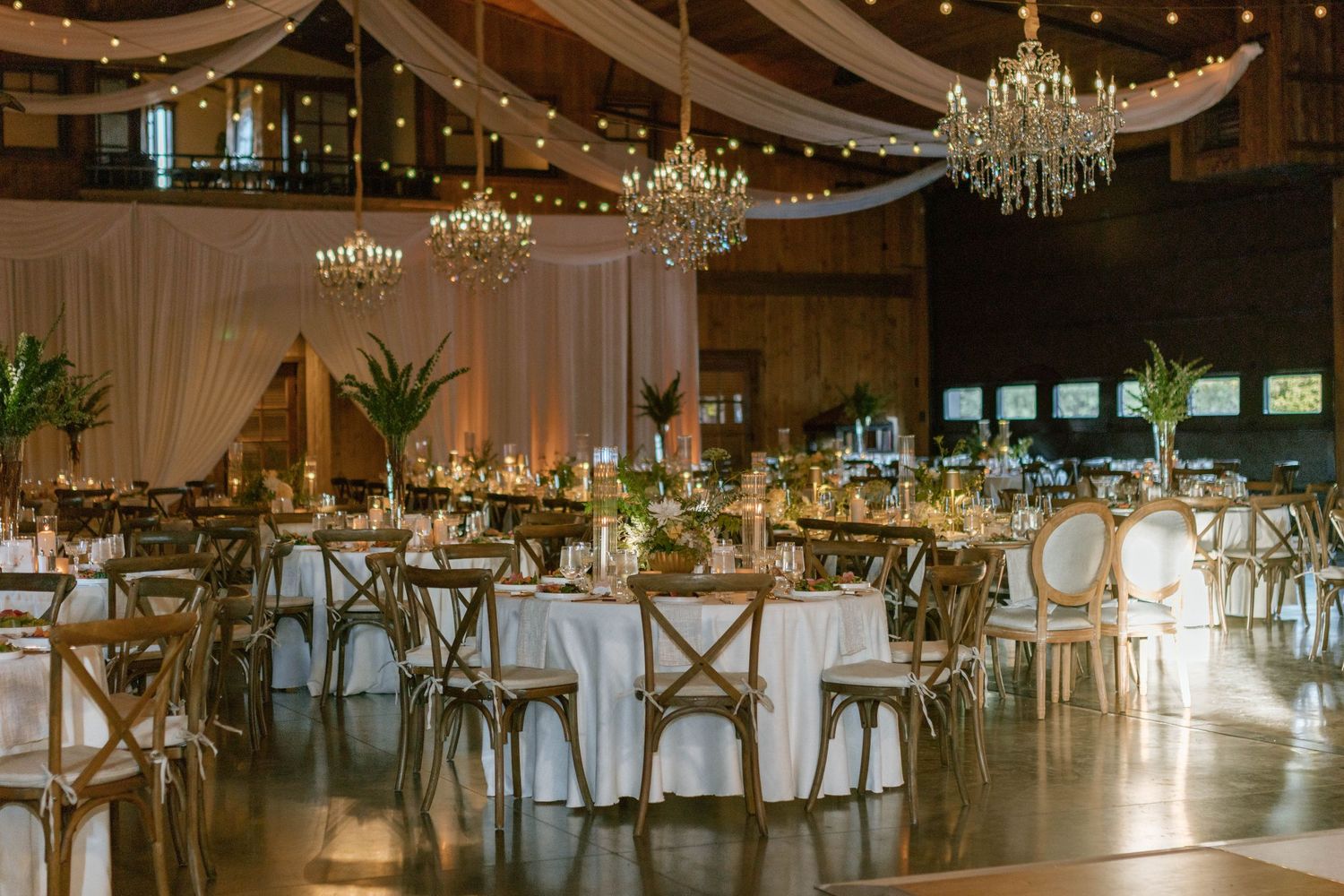 Elegant wedding reception venue with crystal chandeliers and draped white fabric.
