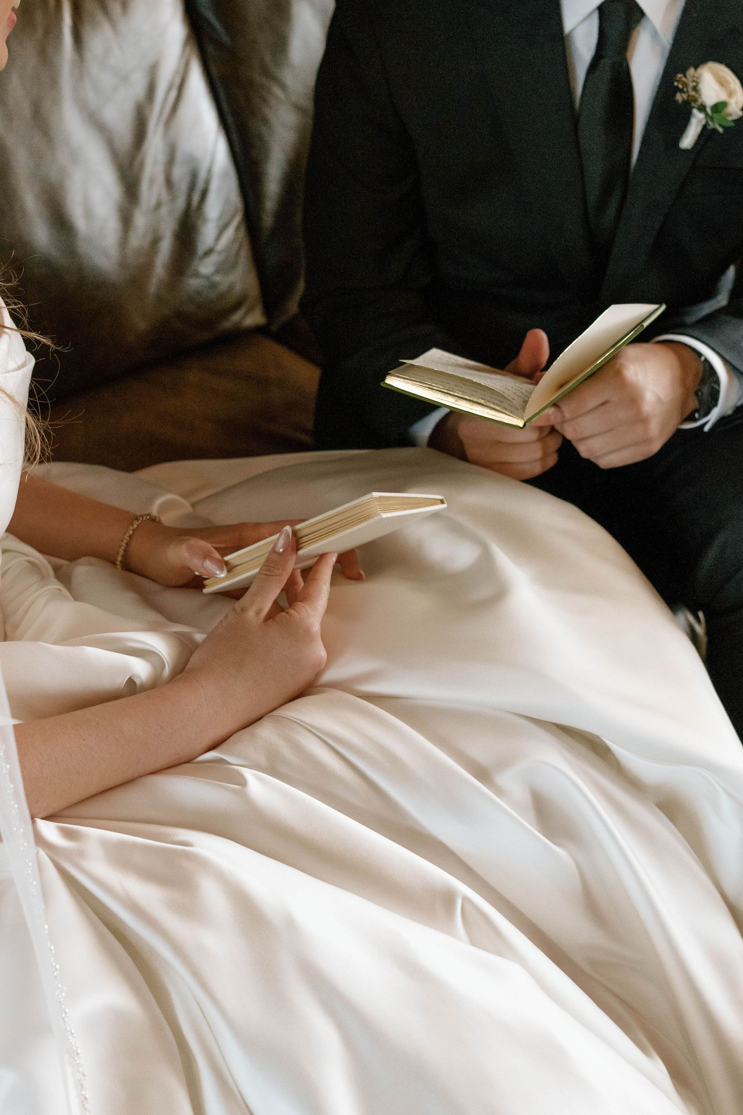 Hands rest on white wedding dress fabric while holding handwritten notes.