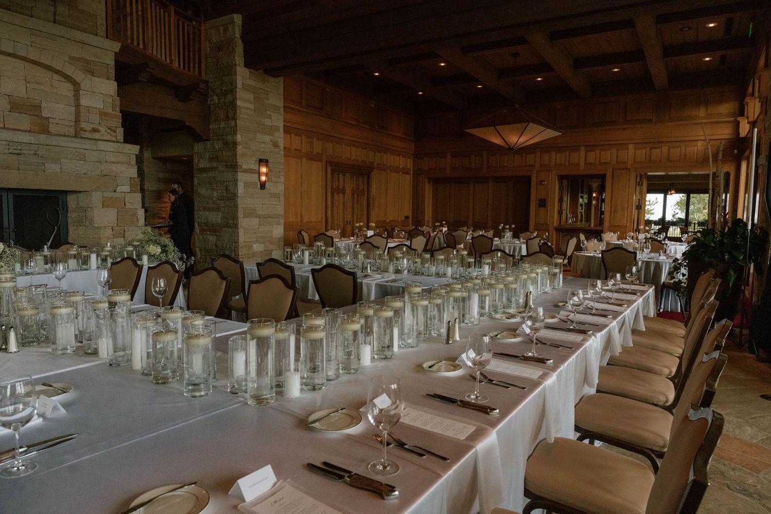 An elegant wedding reception venue with long tables set with white linens and formal place settings.