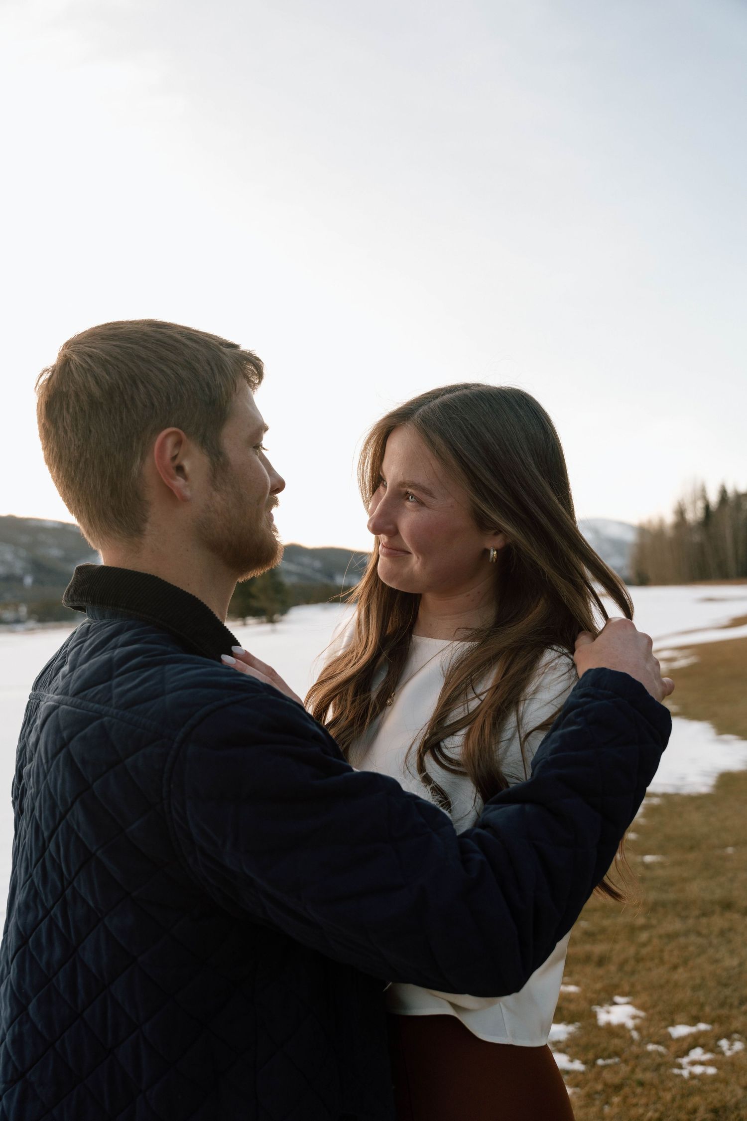 Intimate couple portraits captured against a winter mountain landscape at sunset.