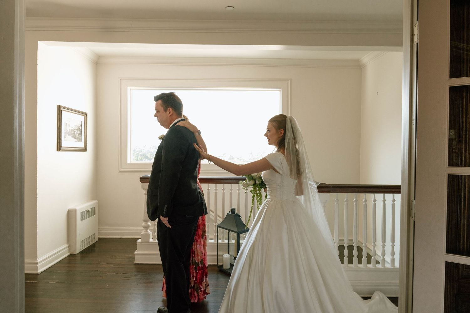 A wedding dress silhouette is visible in a bright, minimalist hallway.