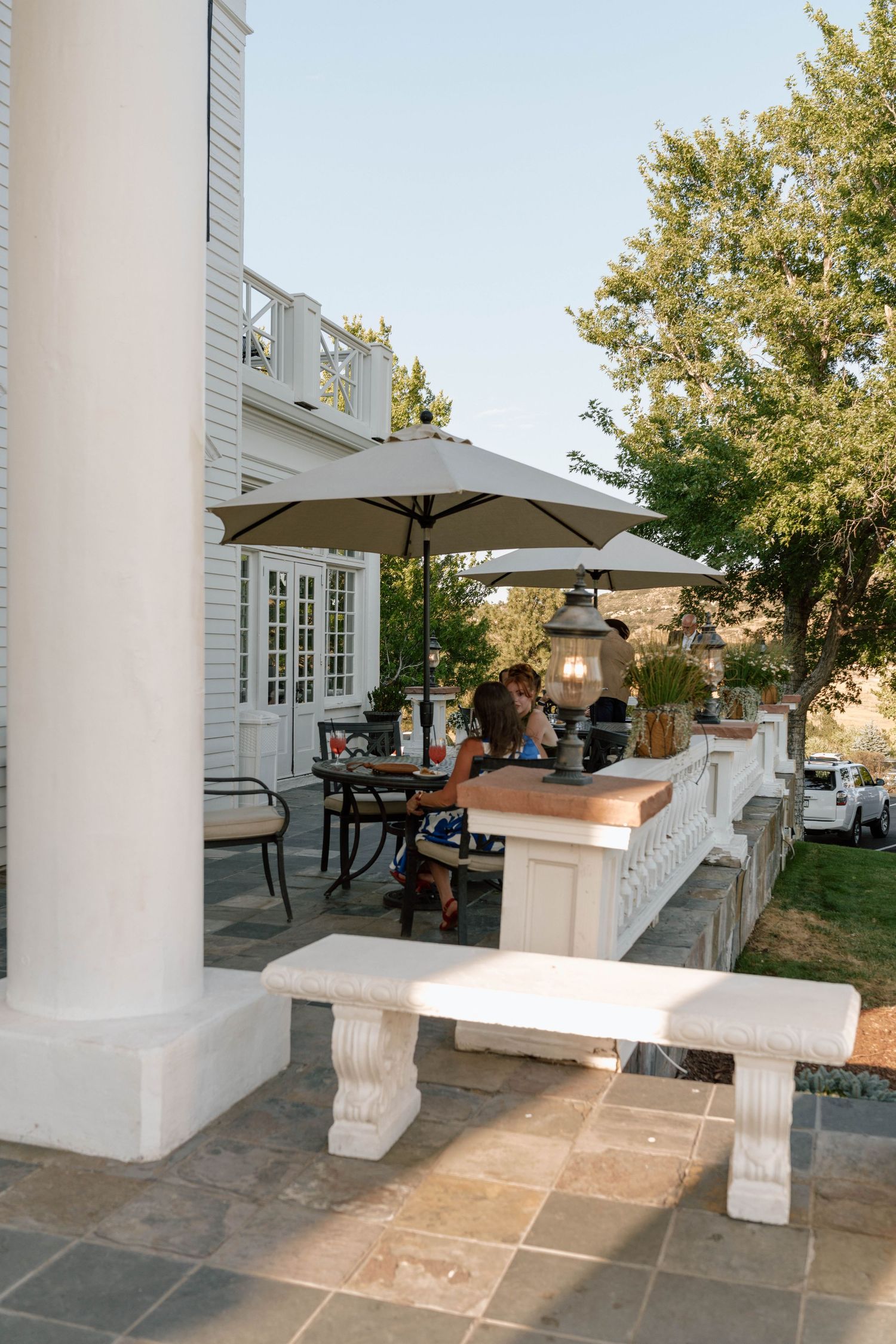 White pillared patio area with stone flooring and outdoor furniture at an elegant venue.