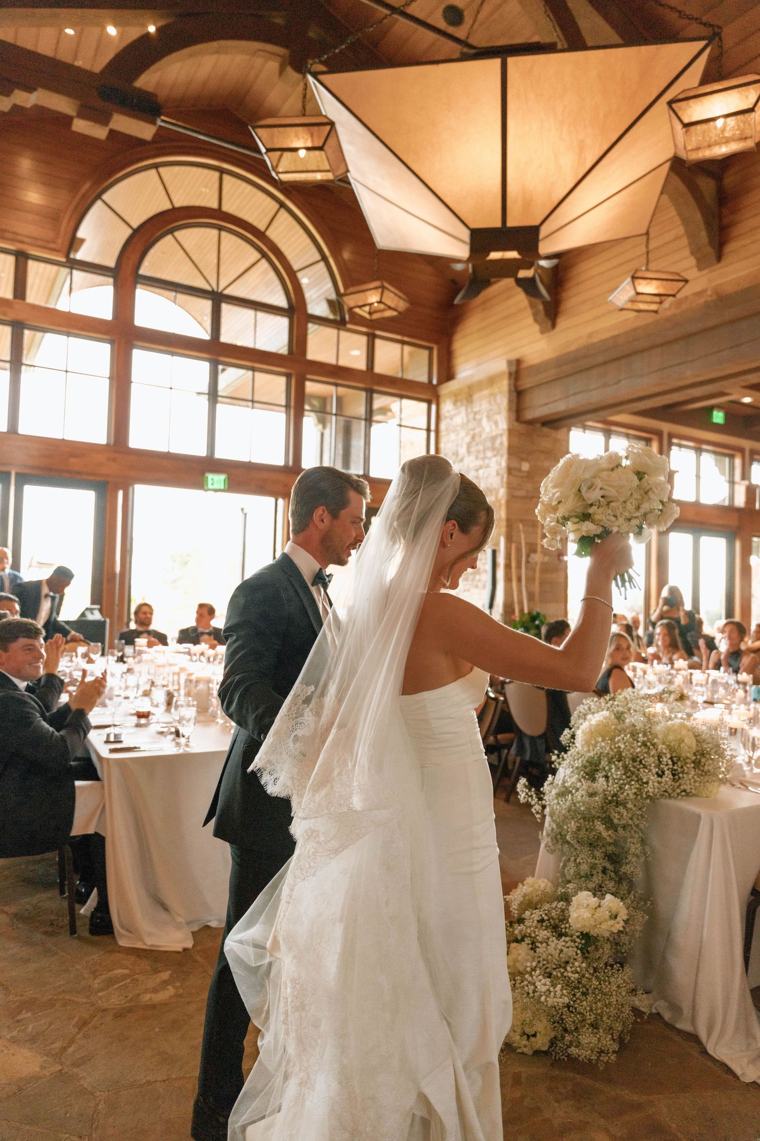 Wedding reception venue with vaulted wooden ceilings and elegant white table settings.
