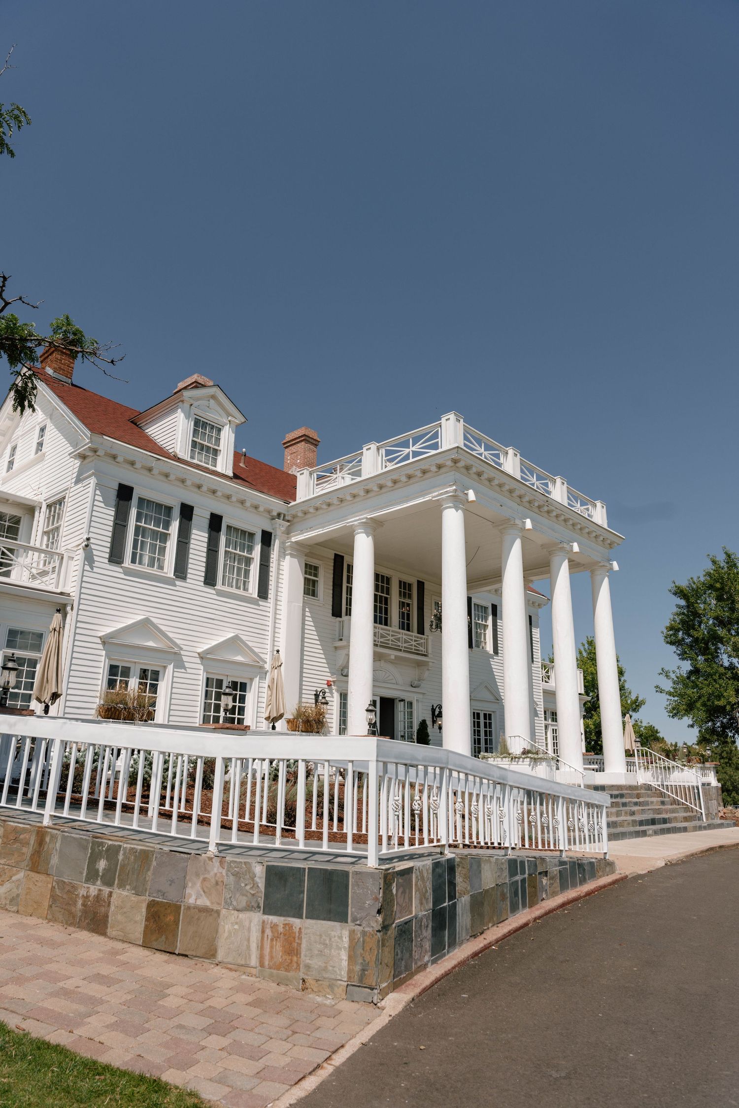 Grand white colonial mansion with pillars and balconies photographed from a low angle.