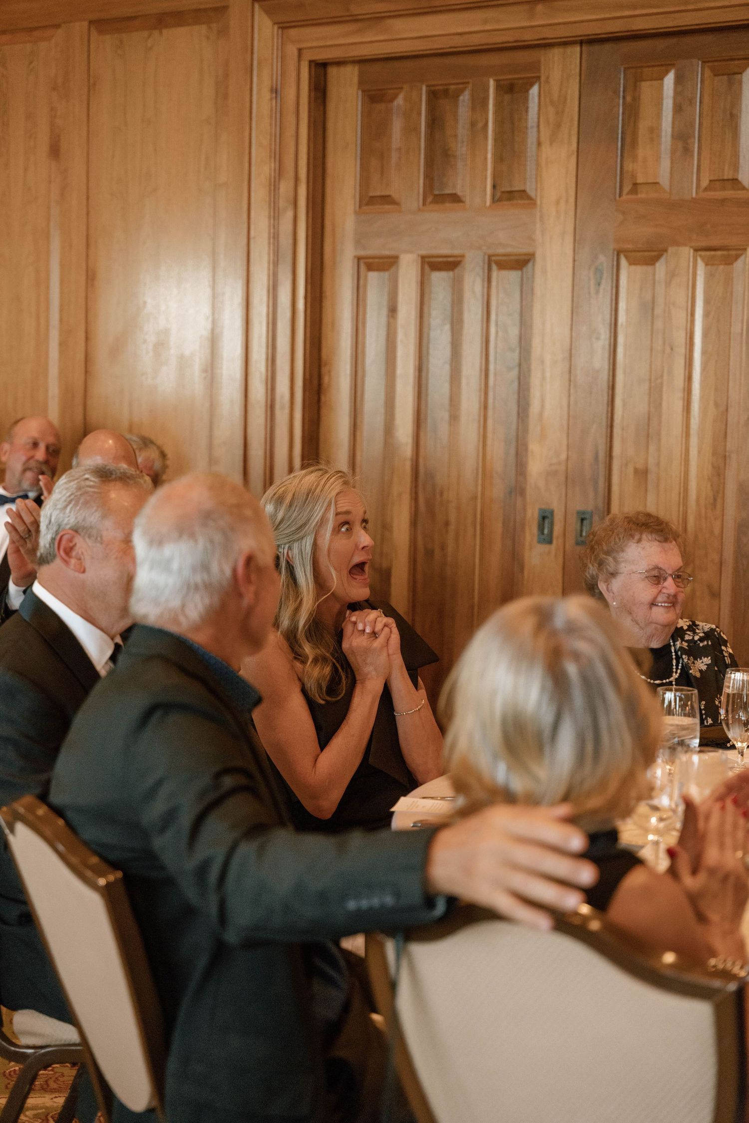 Wedding guests celebrating and raising glasses during reception dinner.