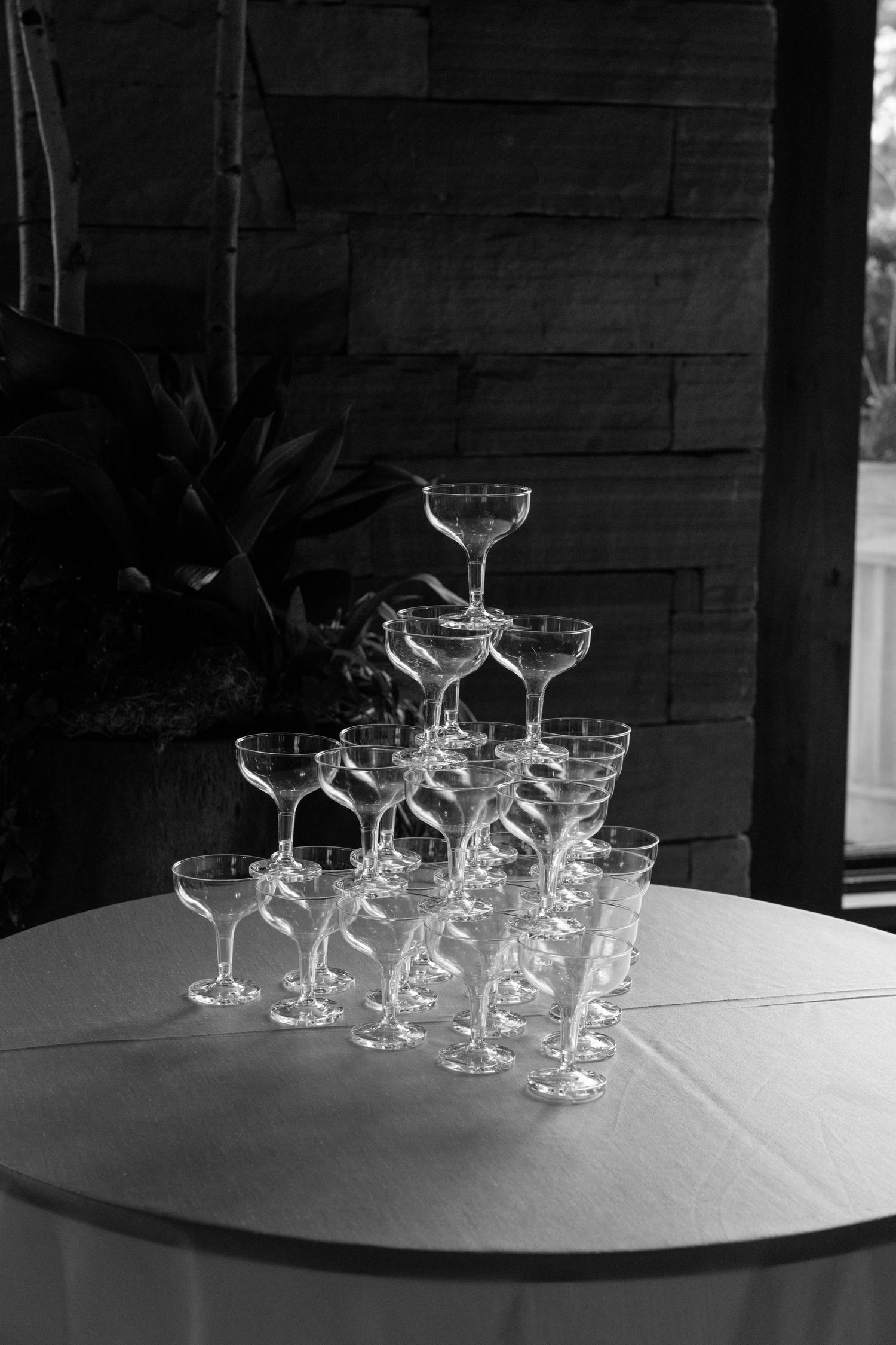 Elegant pyramid of champagne coupe glasses arranged on a white tablecloth in black and white.