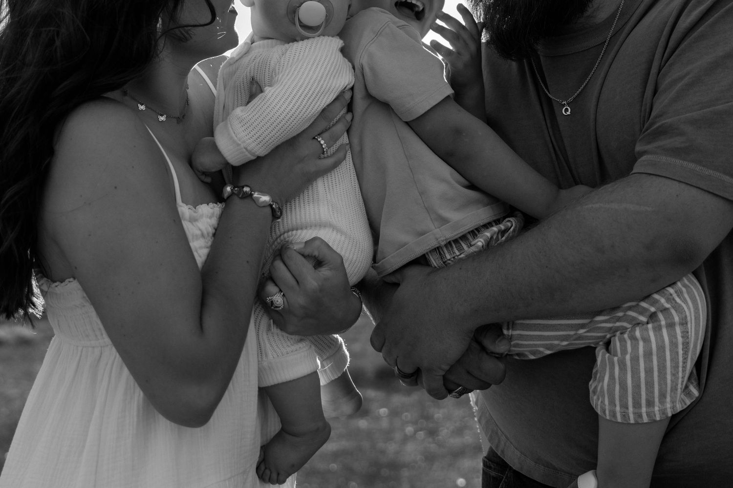 Black and white photo of parents holding their newborn baby together outdoors.