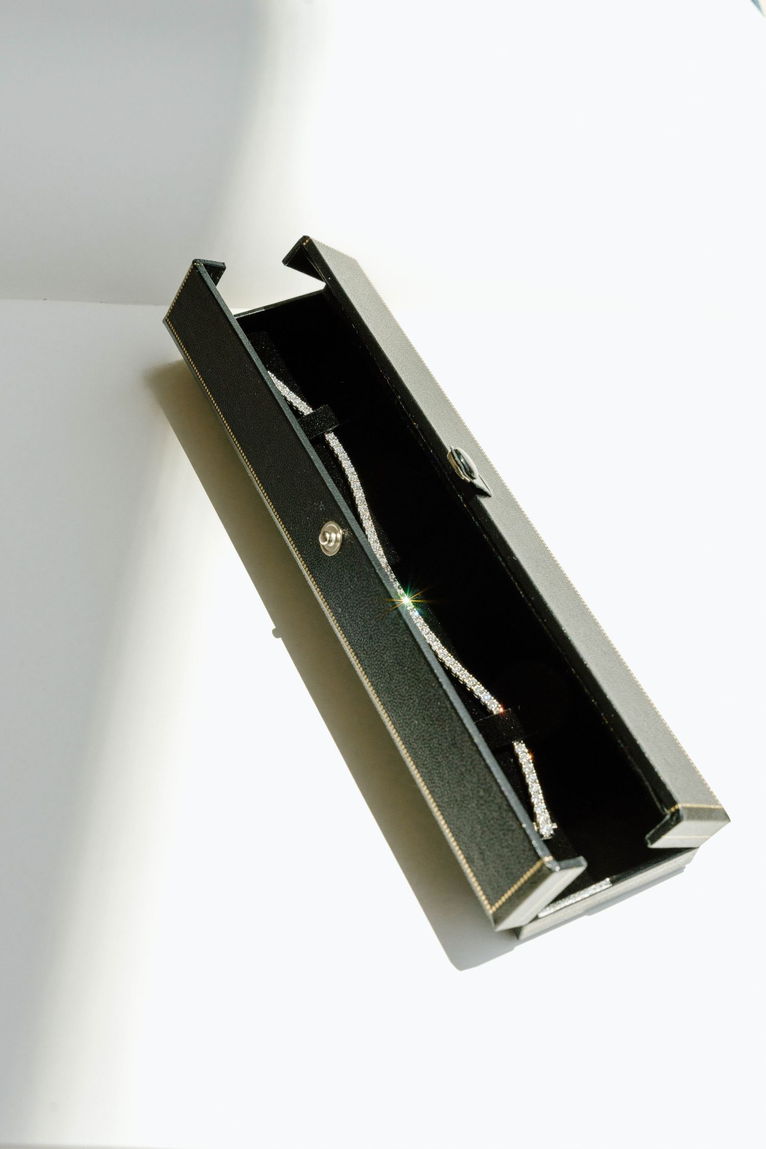 An open black jewelry box photographed from above against a white background.