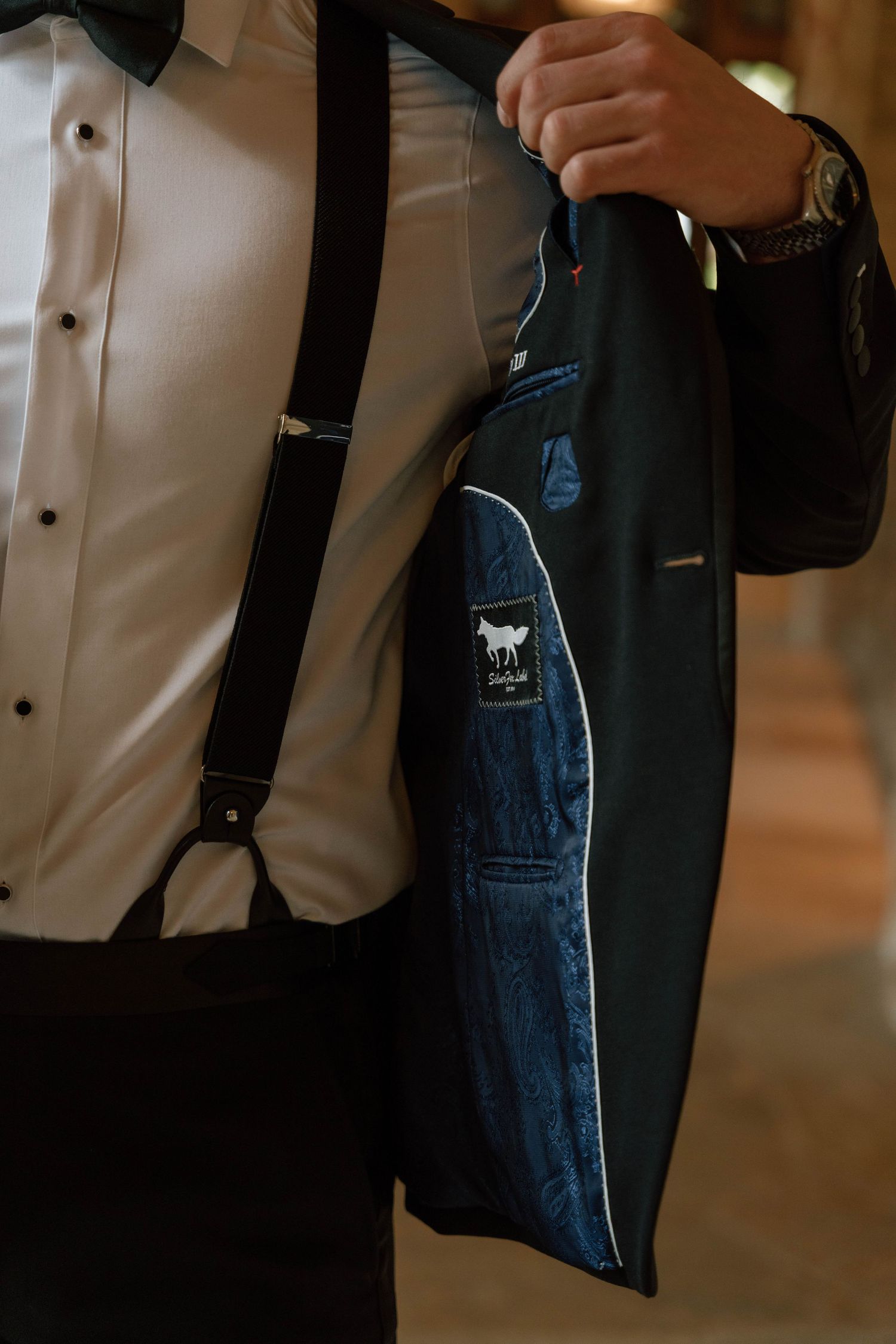 Detail shot of formal wear showing suspenders and a dark suit jacket.