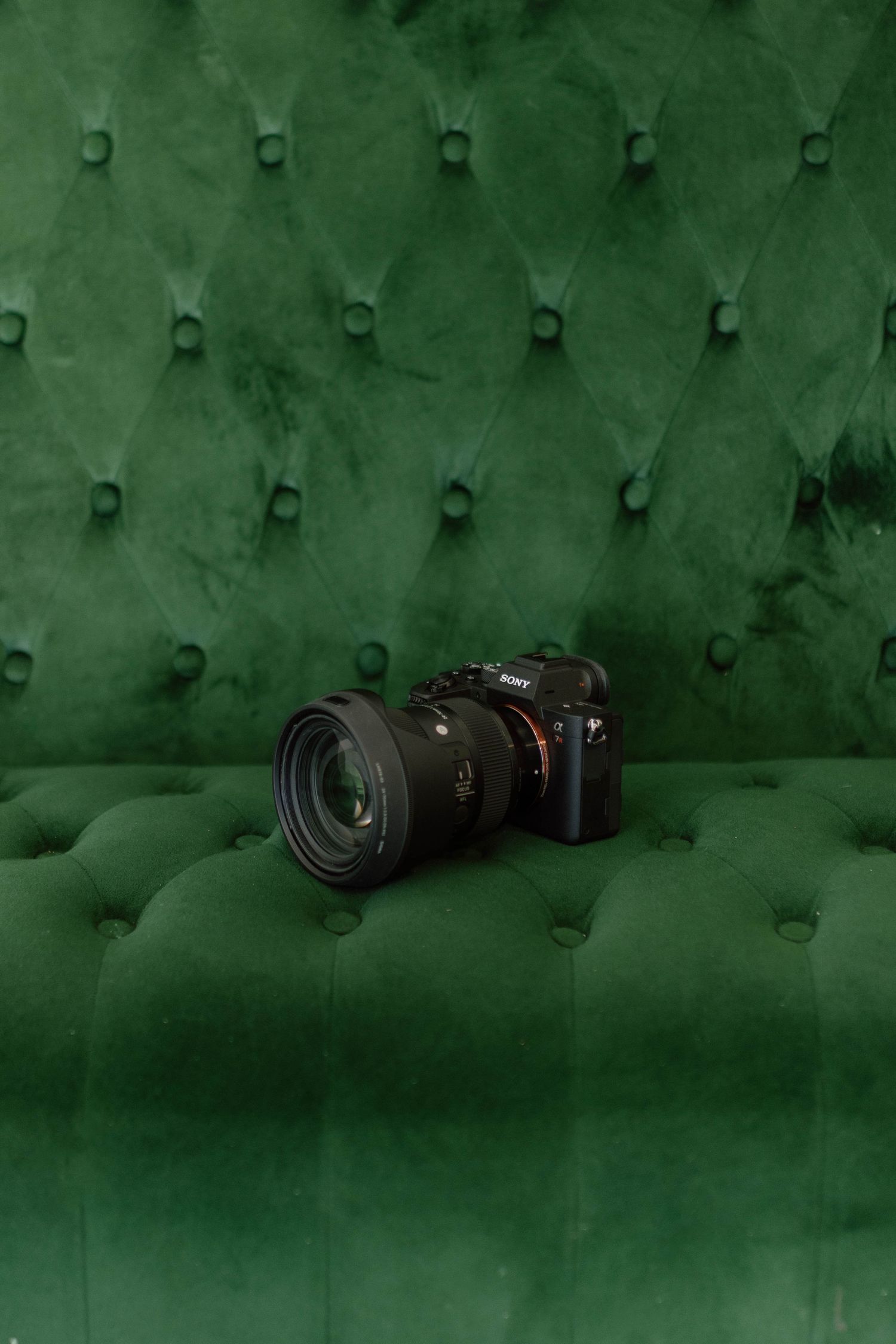 Sony camera with lens resting on emerald green tufted velvet surface.