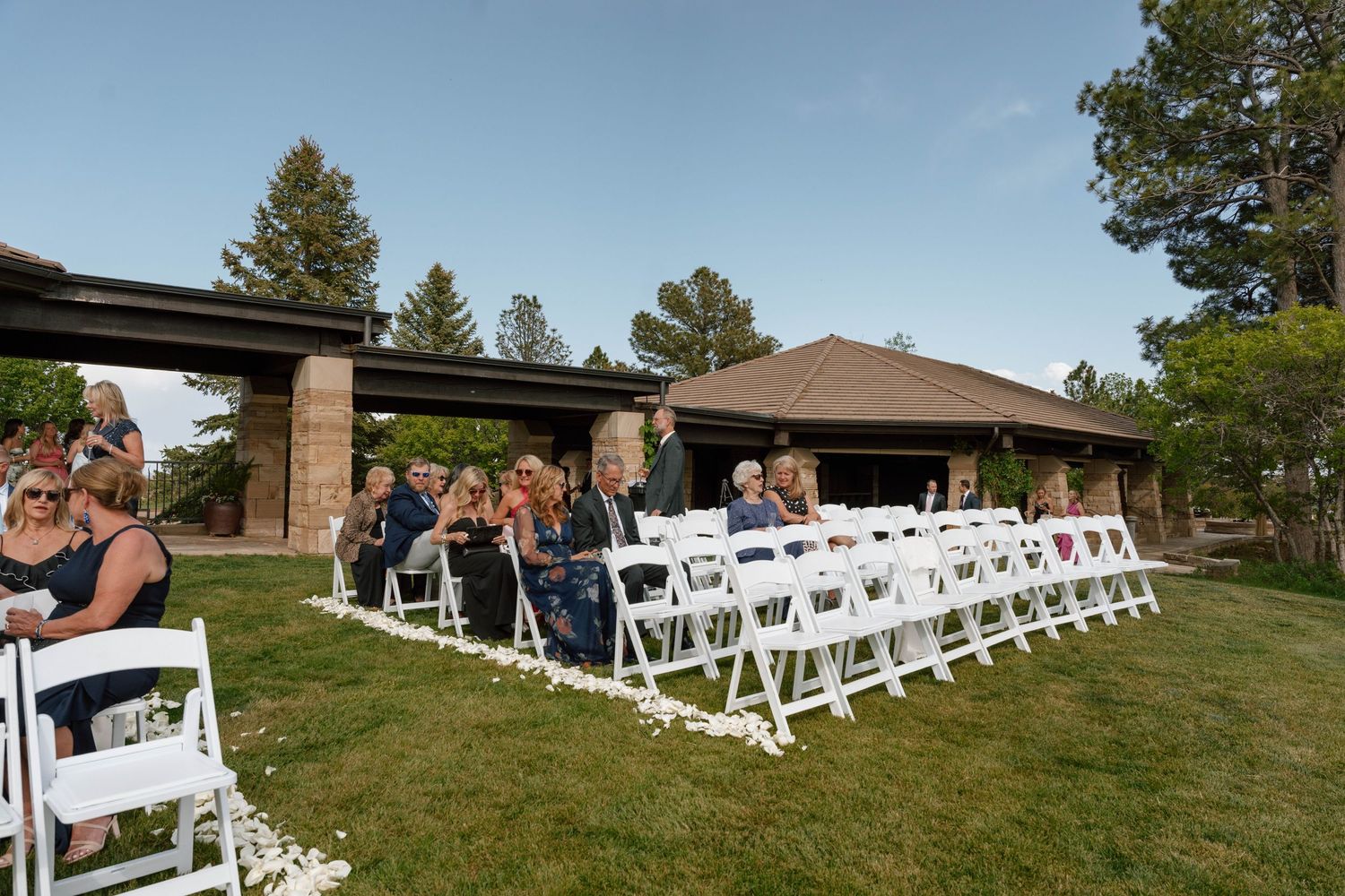 An outdoor wedding ceremony setup with white chairs and a covered pavilion.