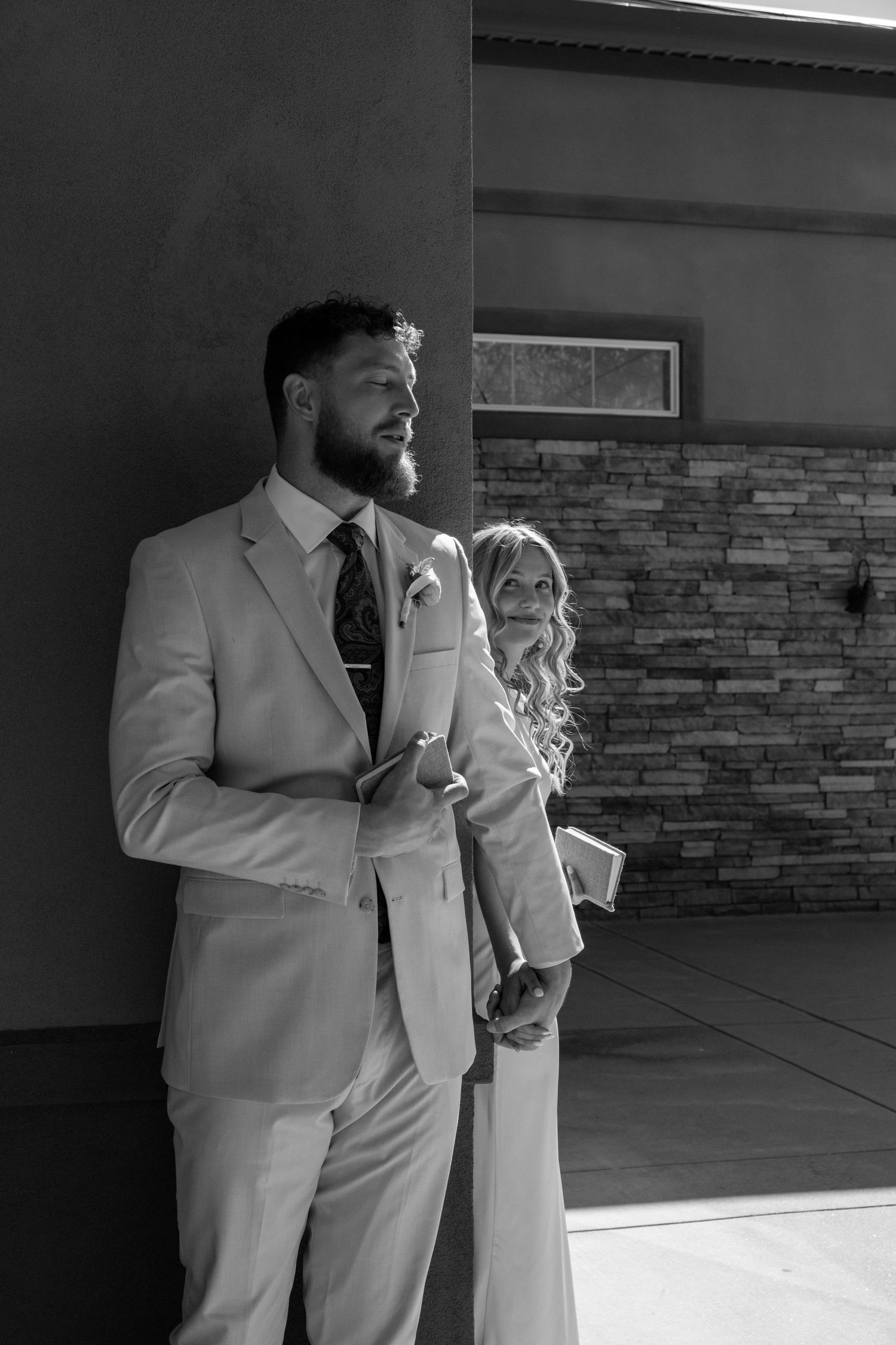 Black and white photo of couple in formal attire sharing an intimate moment.