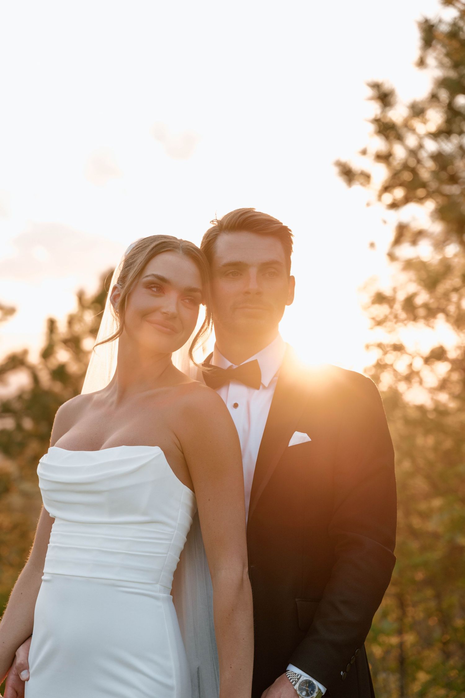 A romantic sunset portrait captures a tender moment between newlyweds against a glowing sky.