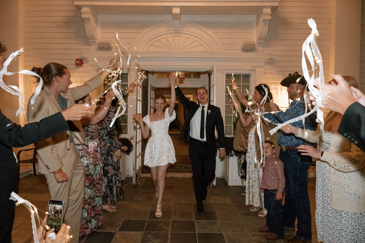 Wedding party dancing and celebrating in an elegant ballroom with decorative architectural details.