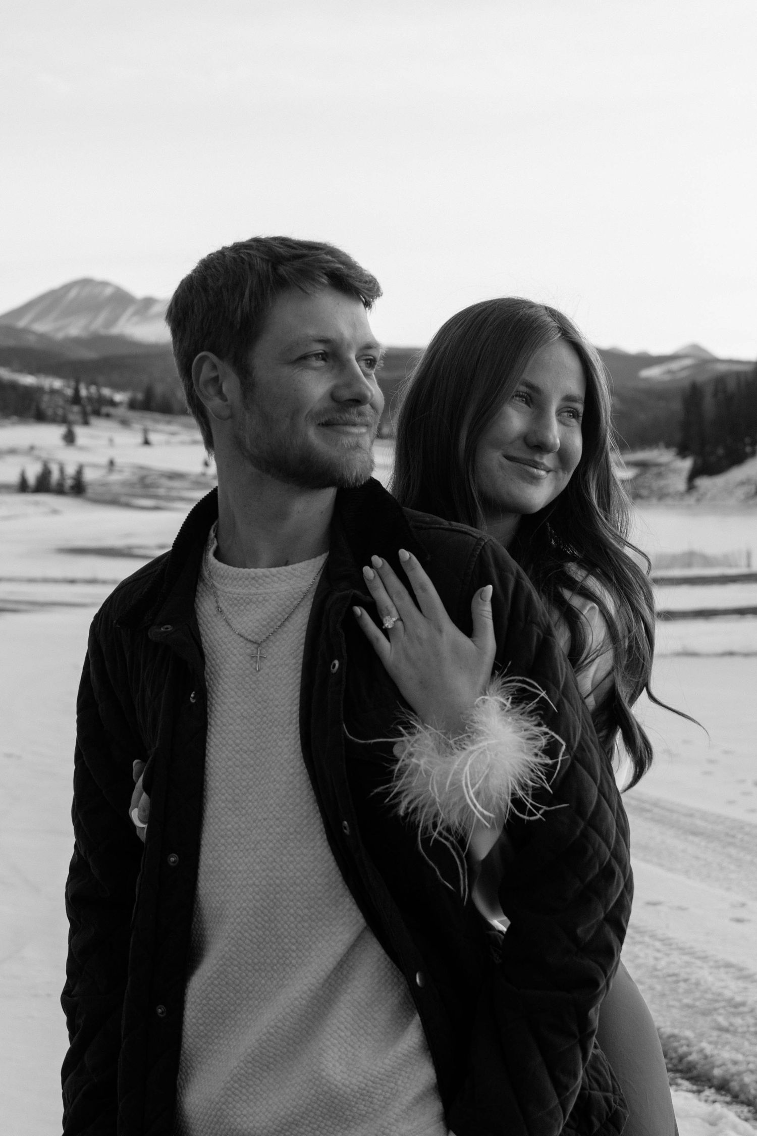 Candid black and white photos of a couple sharing intimate moments in a winter landscape.