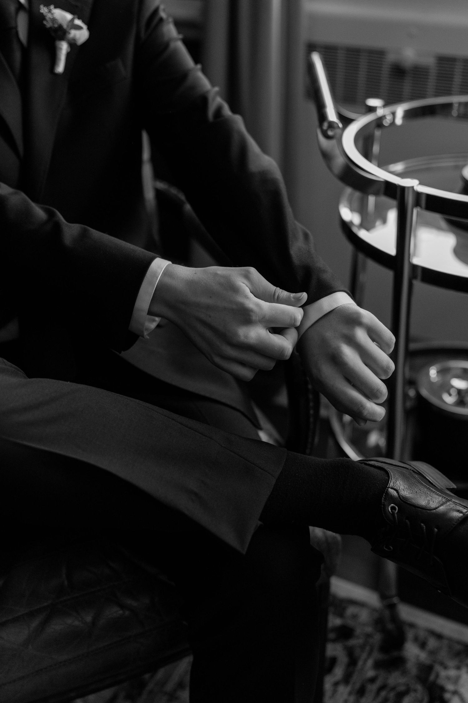 Close-up black and white shots of hands adjusting formal attire.