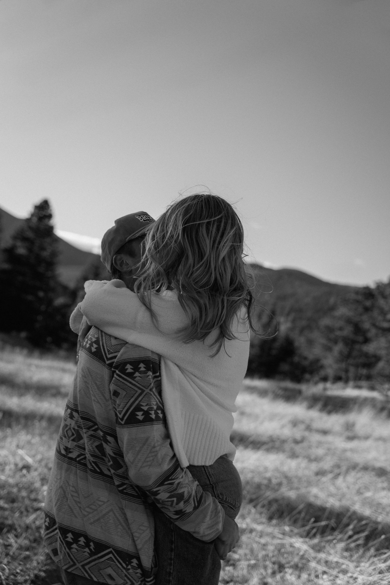 Black and white photograph of embrace in outdoor field setting.