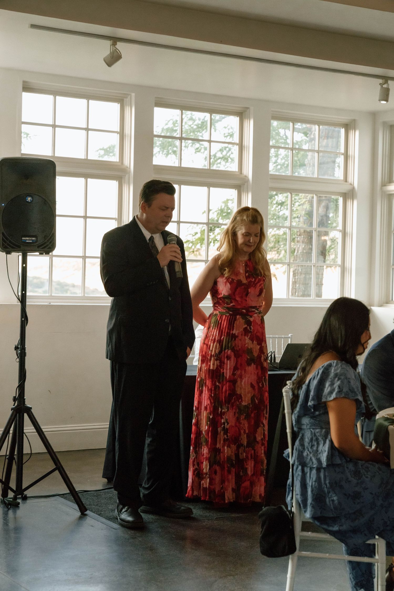 Wedding reception setup with sound equipment and guests gathering in a bright room.