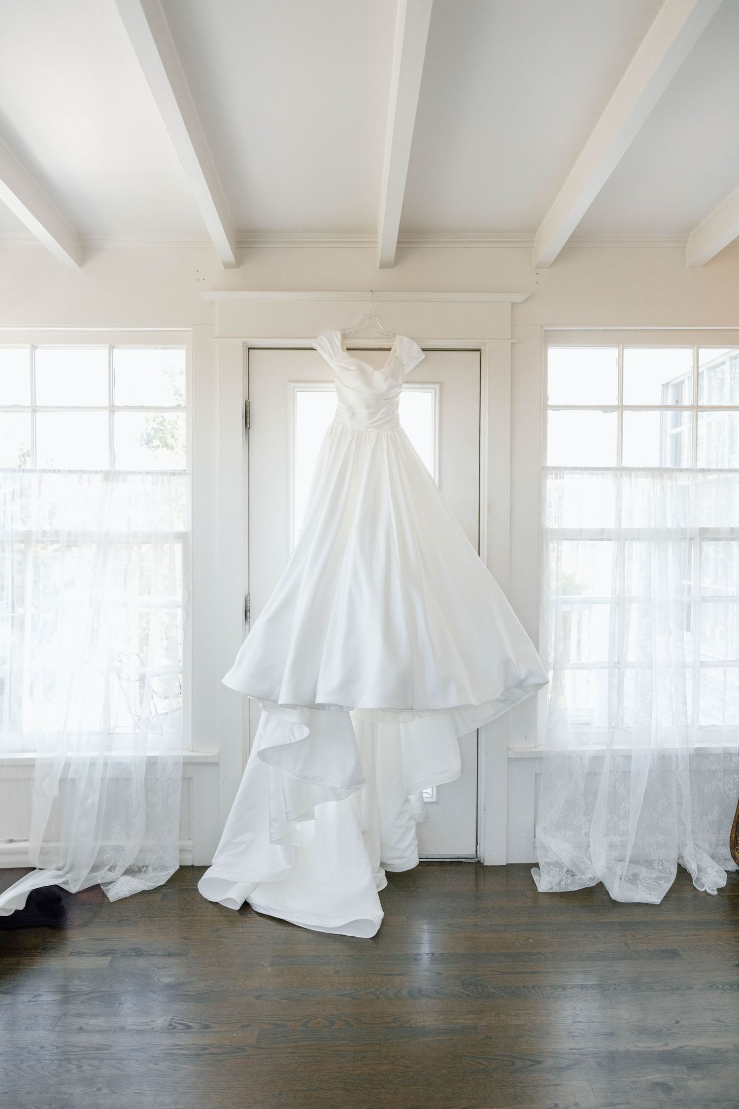 White flowing fabric installations displayed in a minimalist white studio space with wooden floors.
