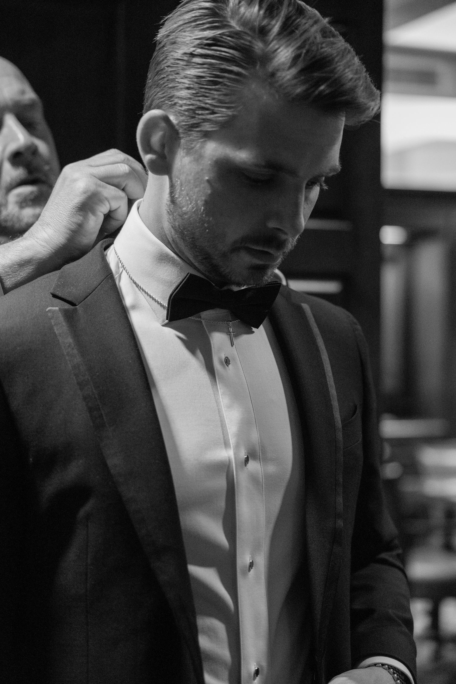 Close-up black and white shot of a formal tuxedo bow tie being adjusted.