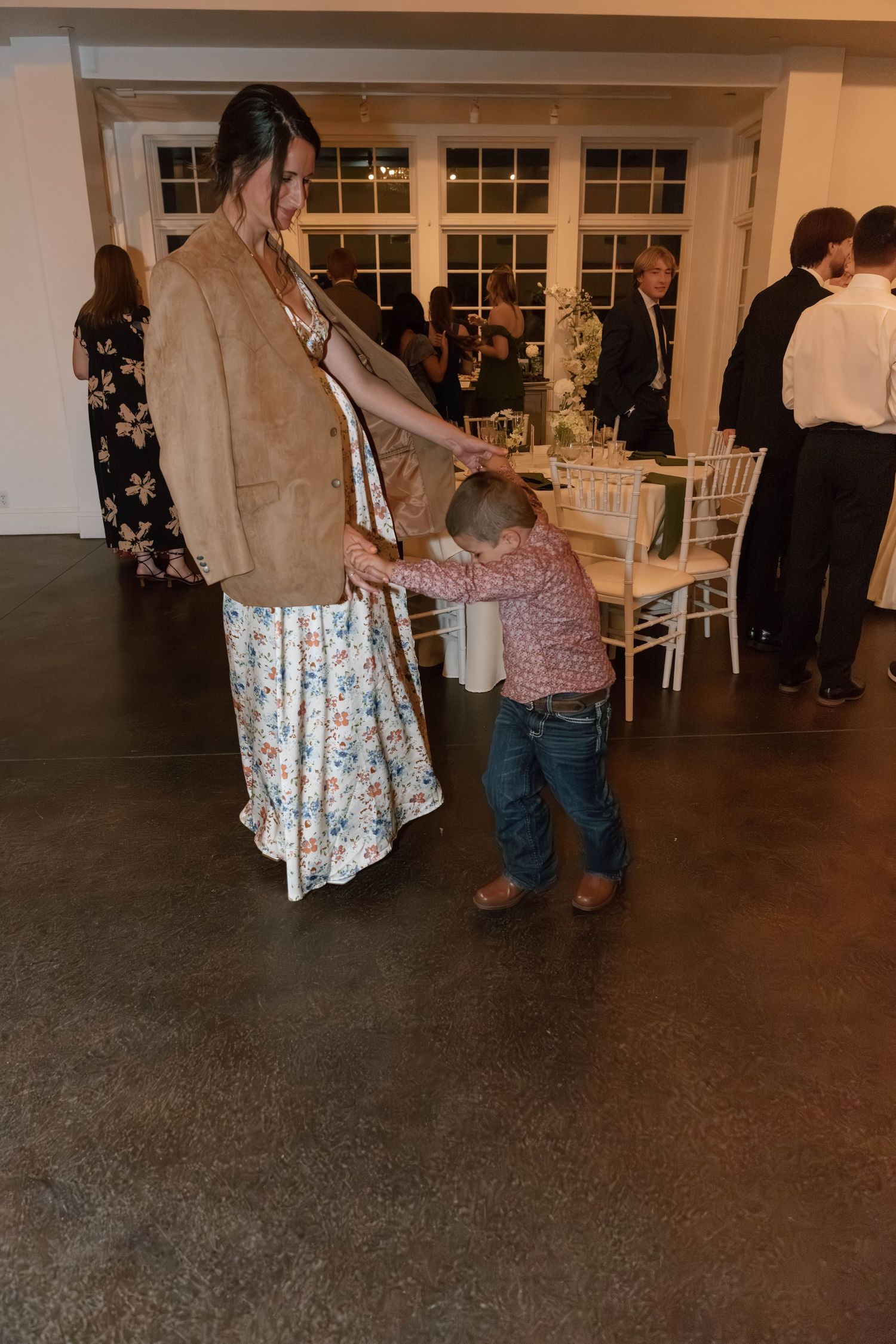 Wedding guests dancing on dark flooring at an indoor reception.
