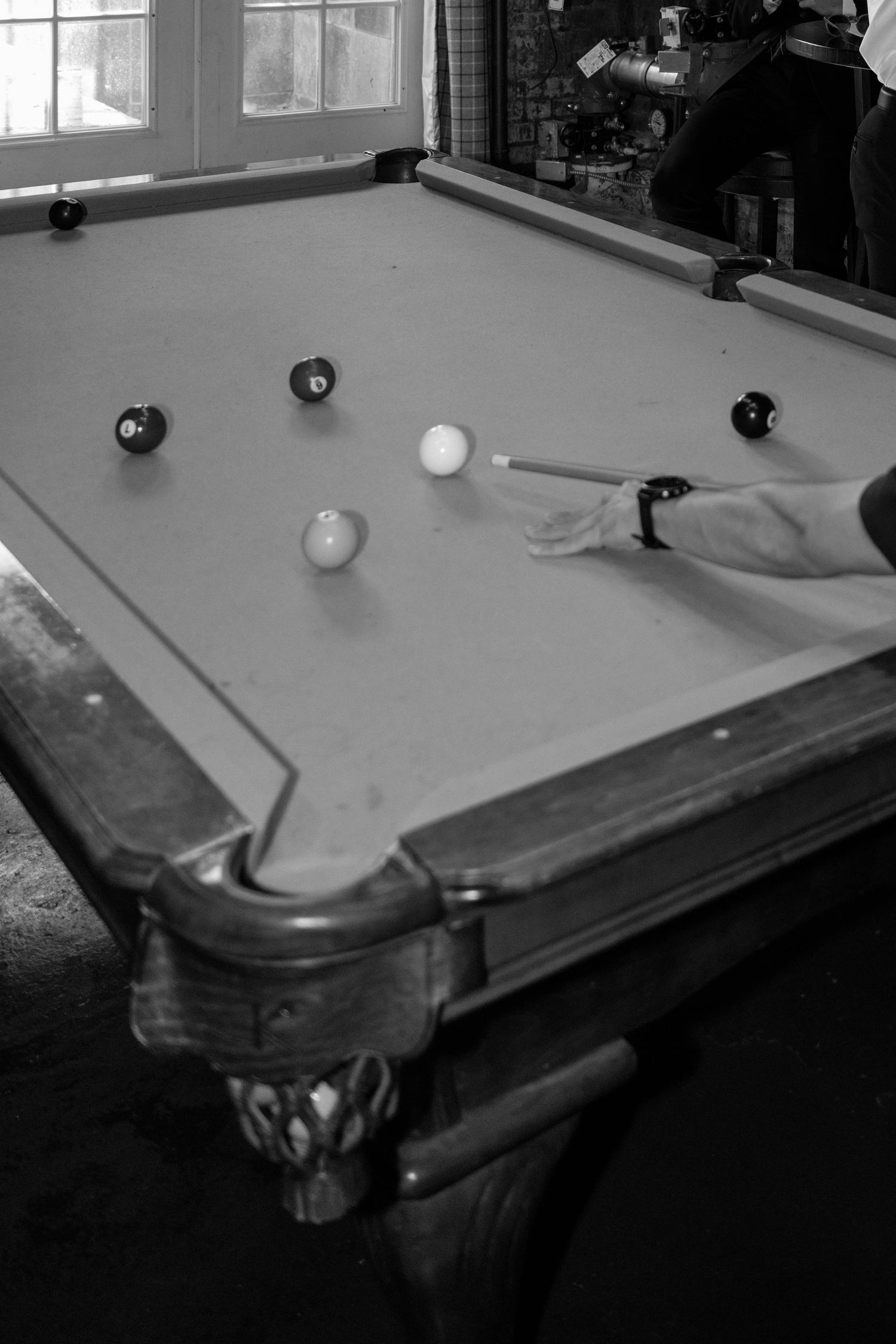 A black and white sequence showing a game of pool being played on a vintage table.