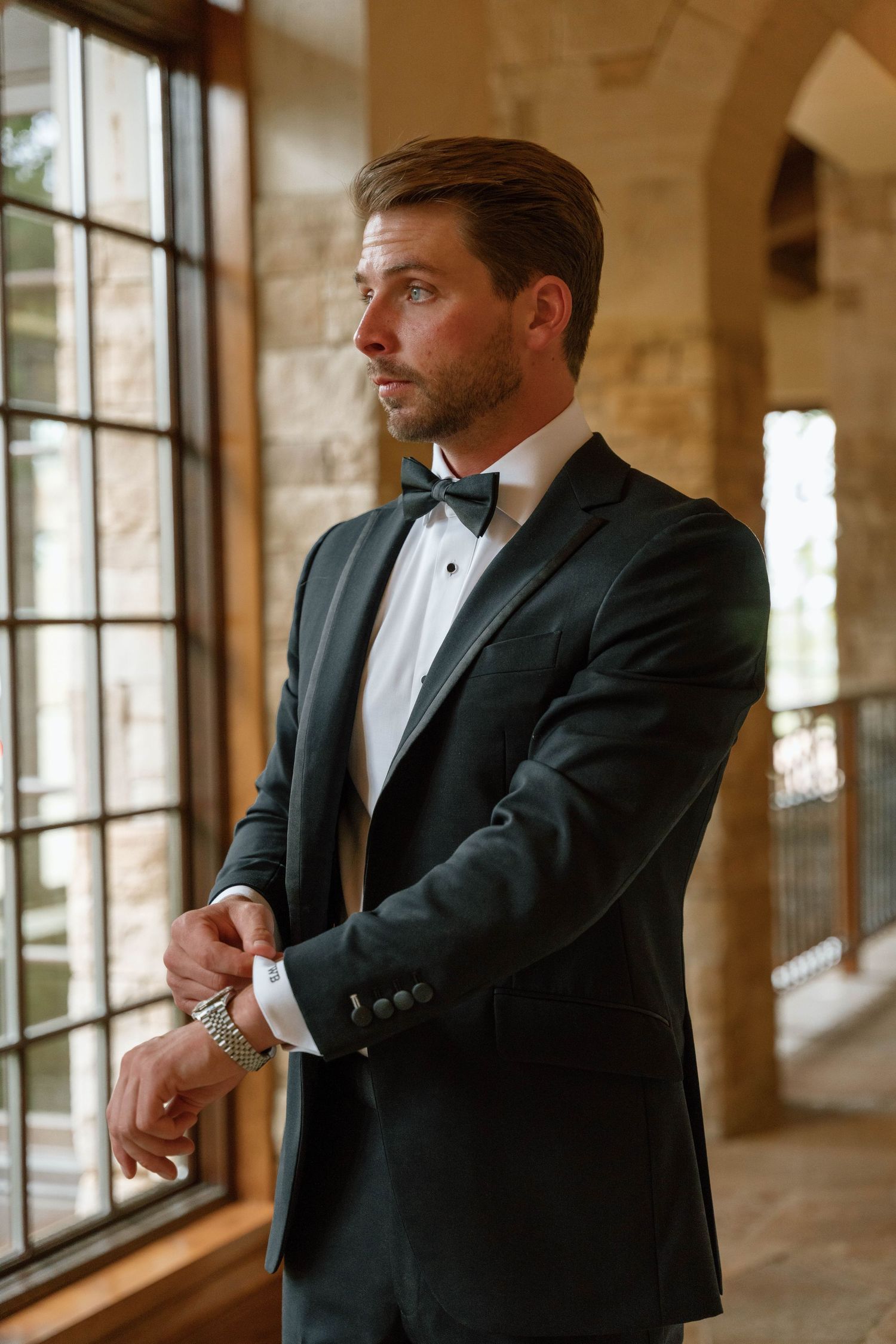 Classic formal portrait by window in stone-walled venue.