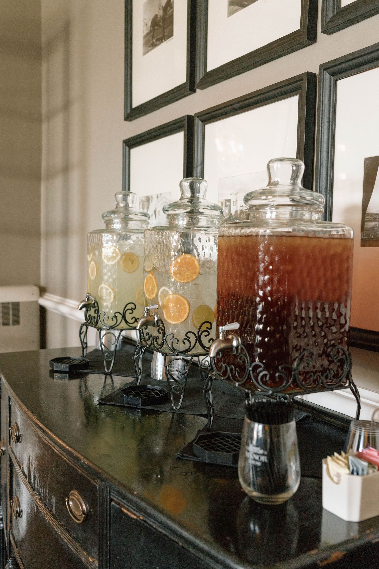 Glass beverage dispensers filled with colorful drinks lined up on a dark counter.