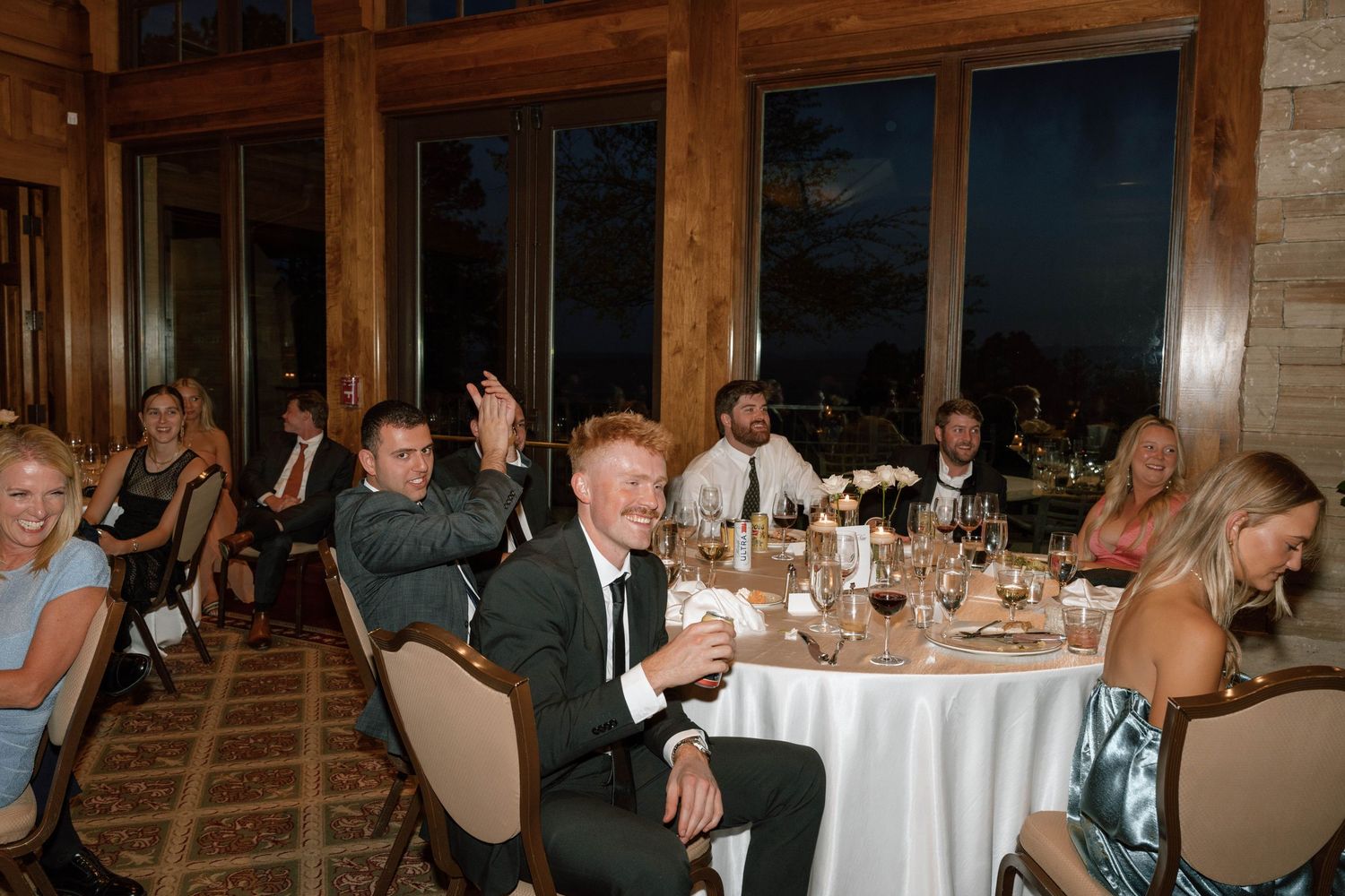 Large banquet hall filled with guests at round tables during an evening celebration.