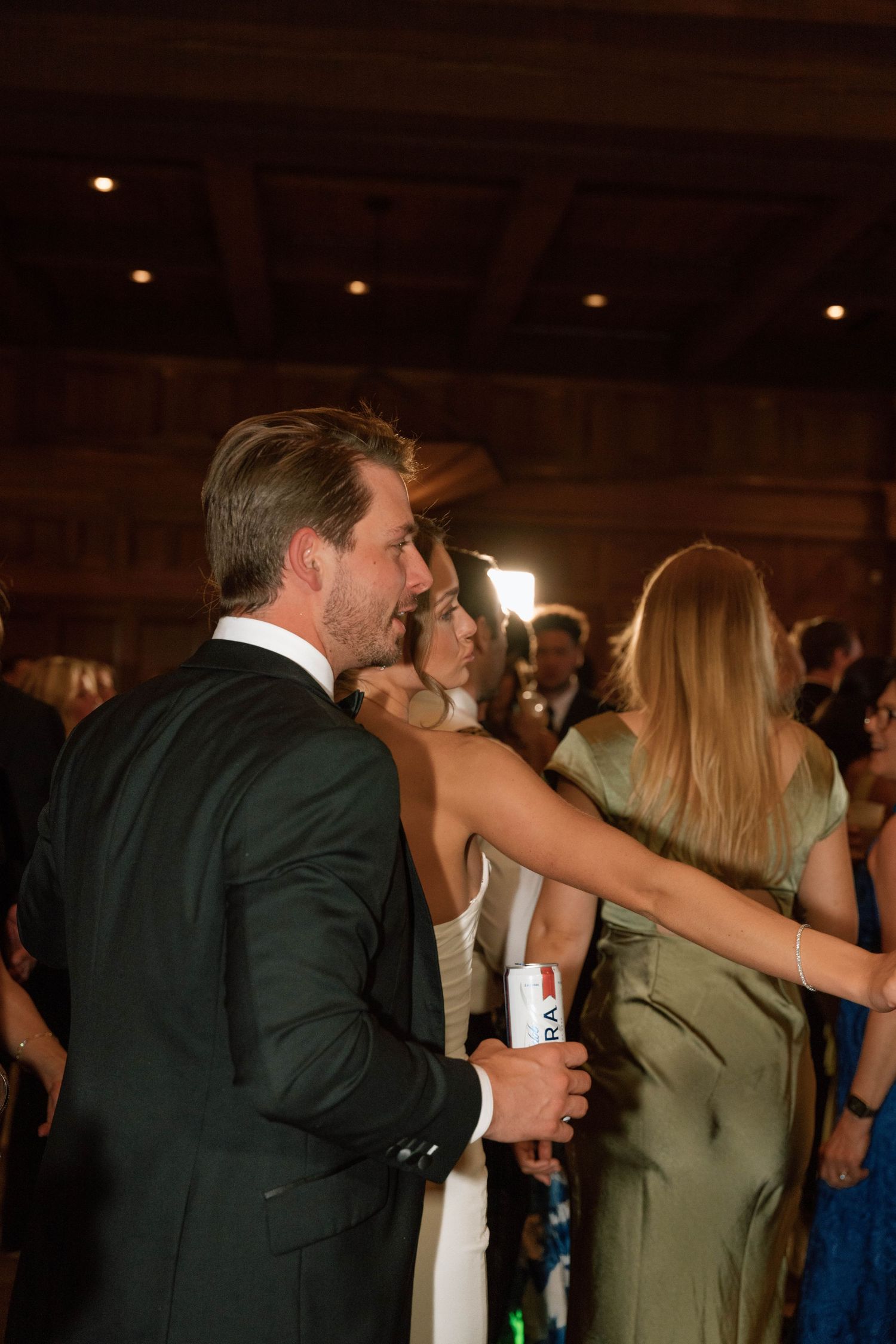 Couples dancing together at an elegant wedding reception with warm lighting.