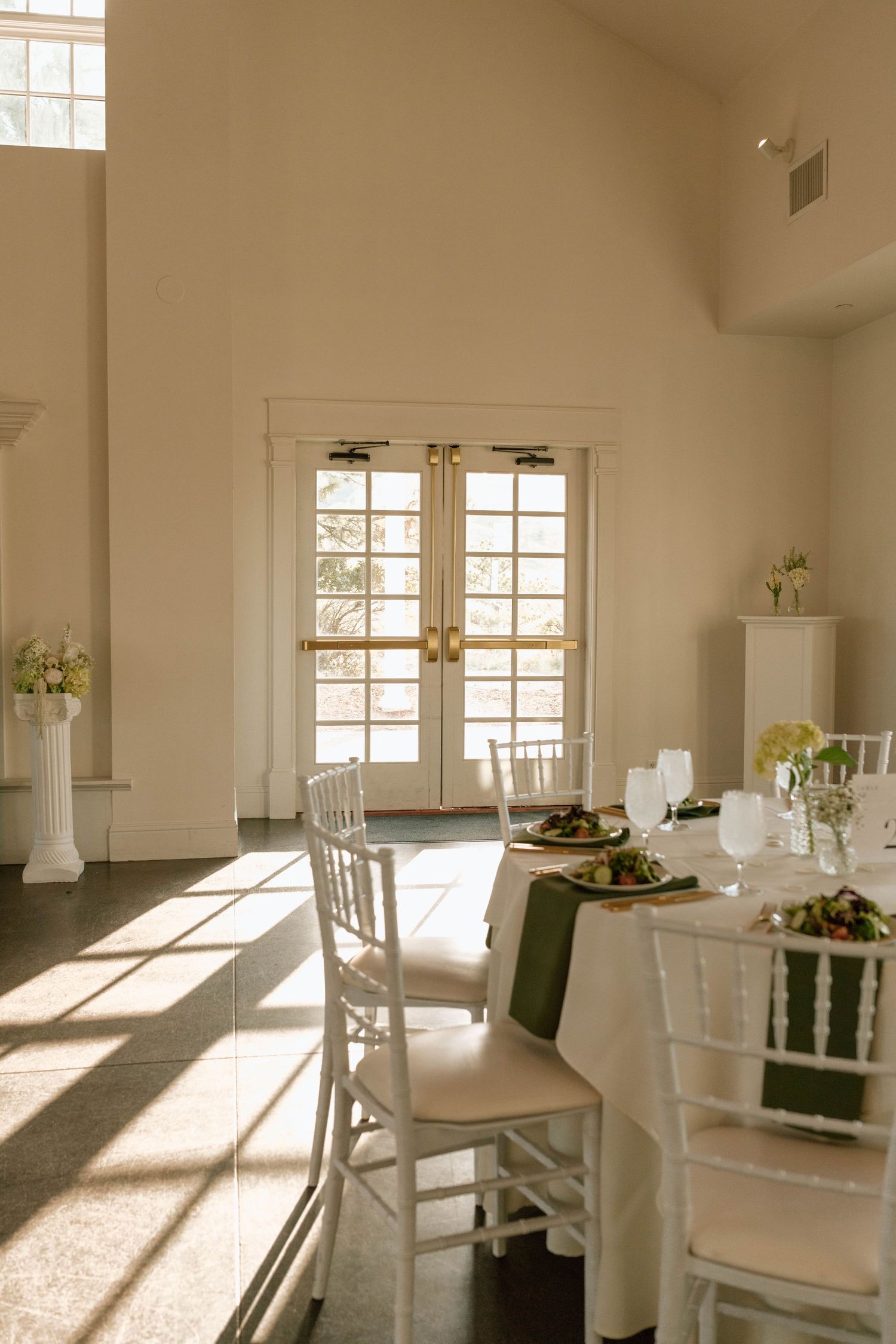 Bright, airy reception room with white tables and chairs set for an elegant event.