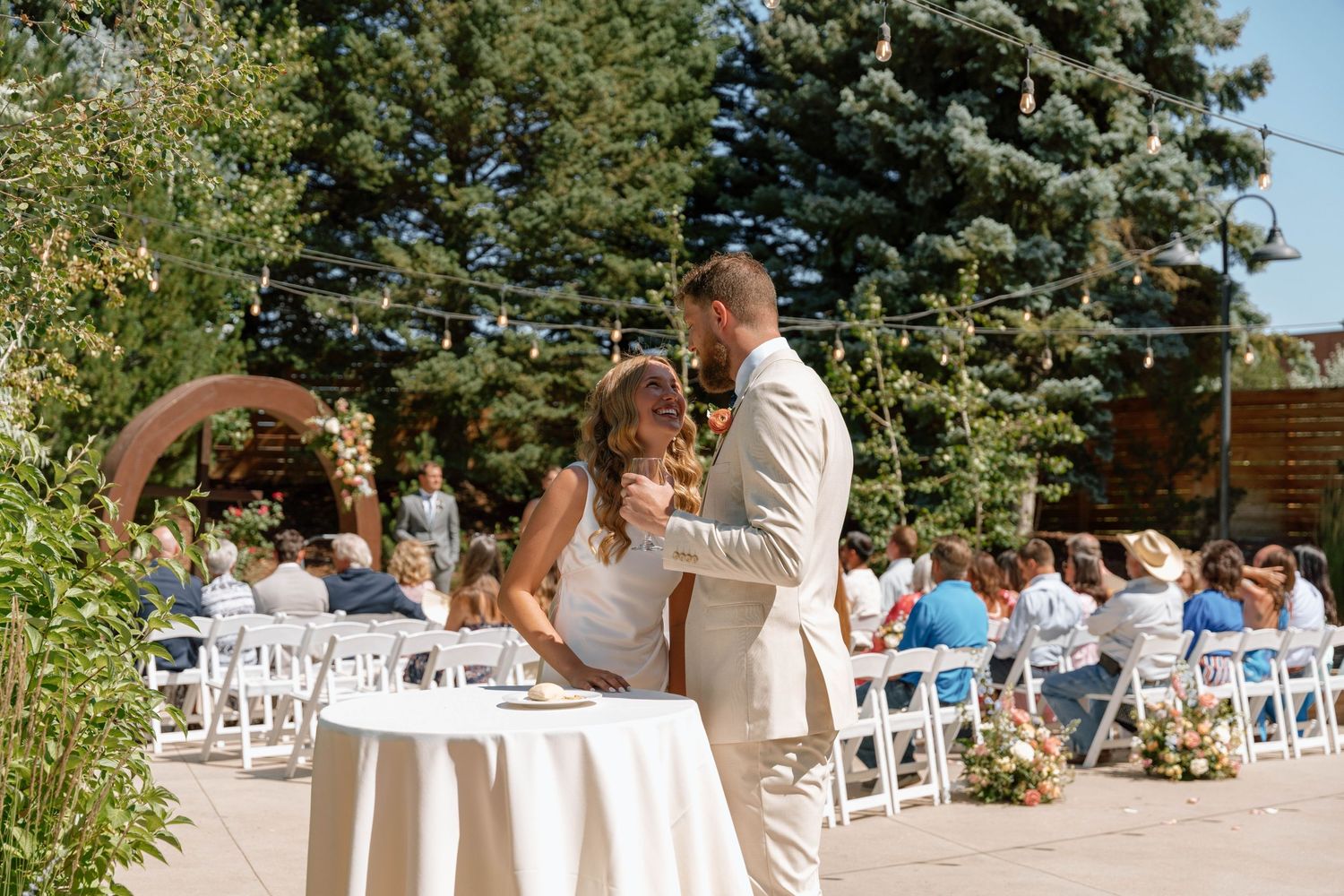 Outdoor wedding ceremony setup with white chairs and natural scenery.