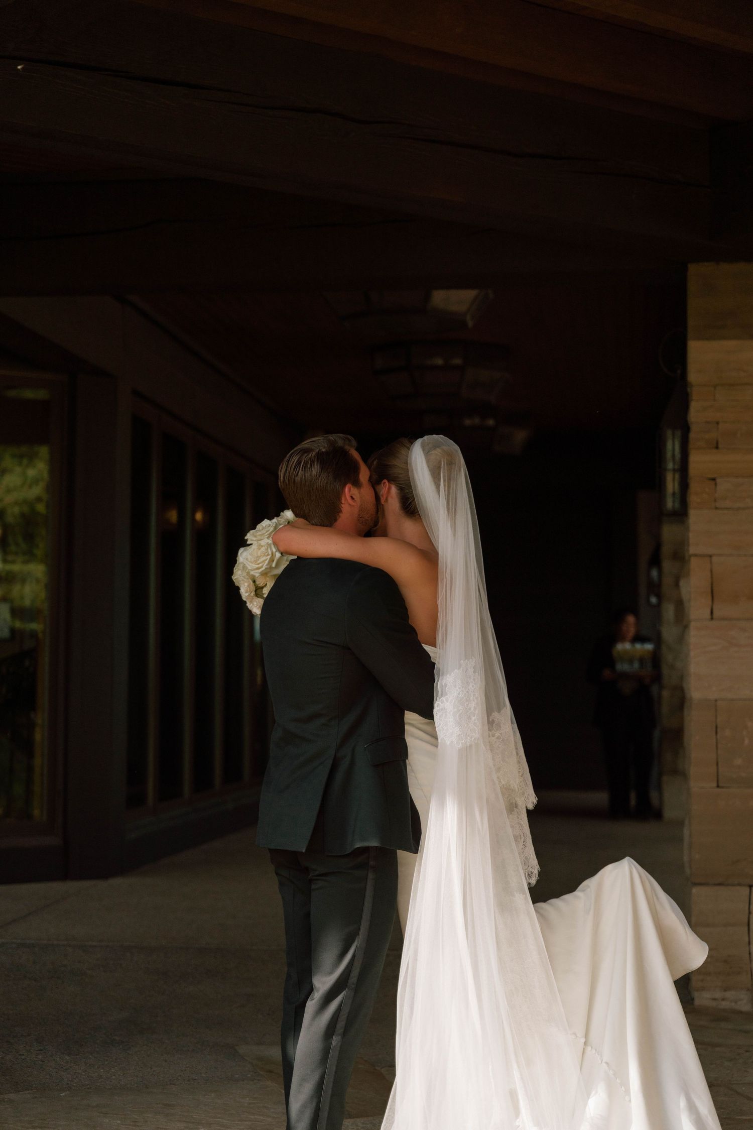 A romantic wedding moment captured in silhouette showing a couple embracing under dim lighting.