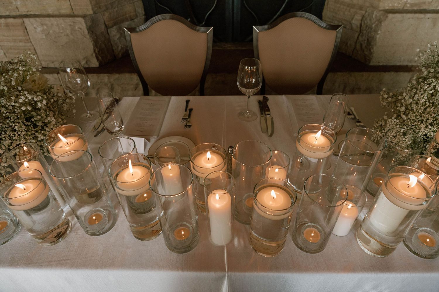 A row of glowing candles in glass holders creates romantic ambiance at a wedding reception.