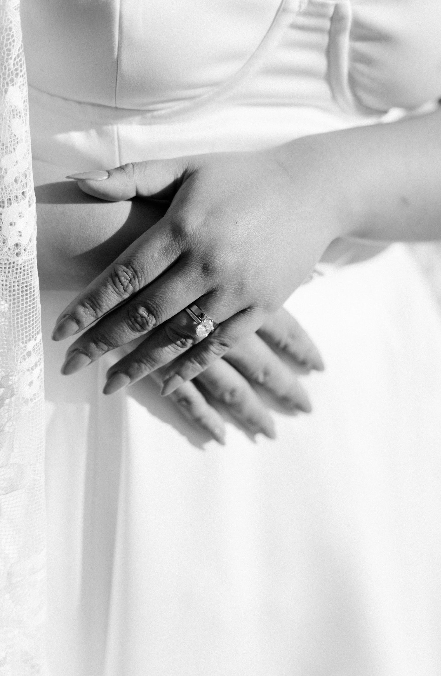 Close-up black and white image of hands exchanging wedding rings during a ceremony.