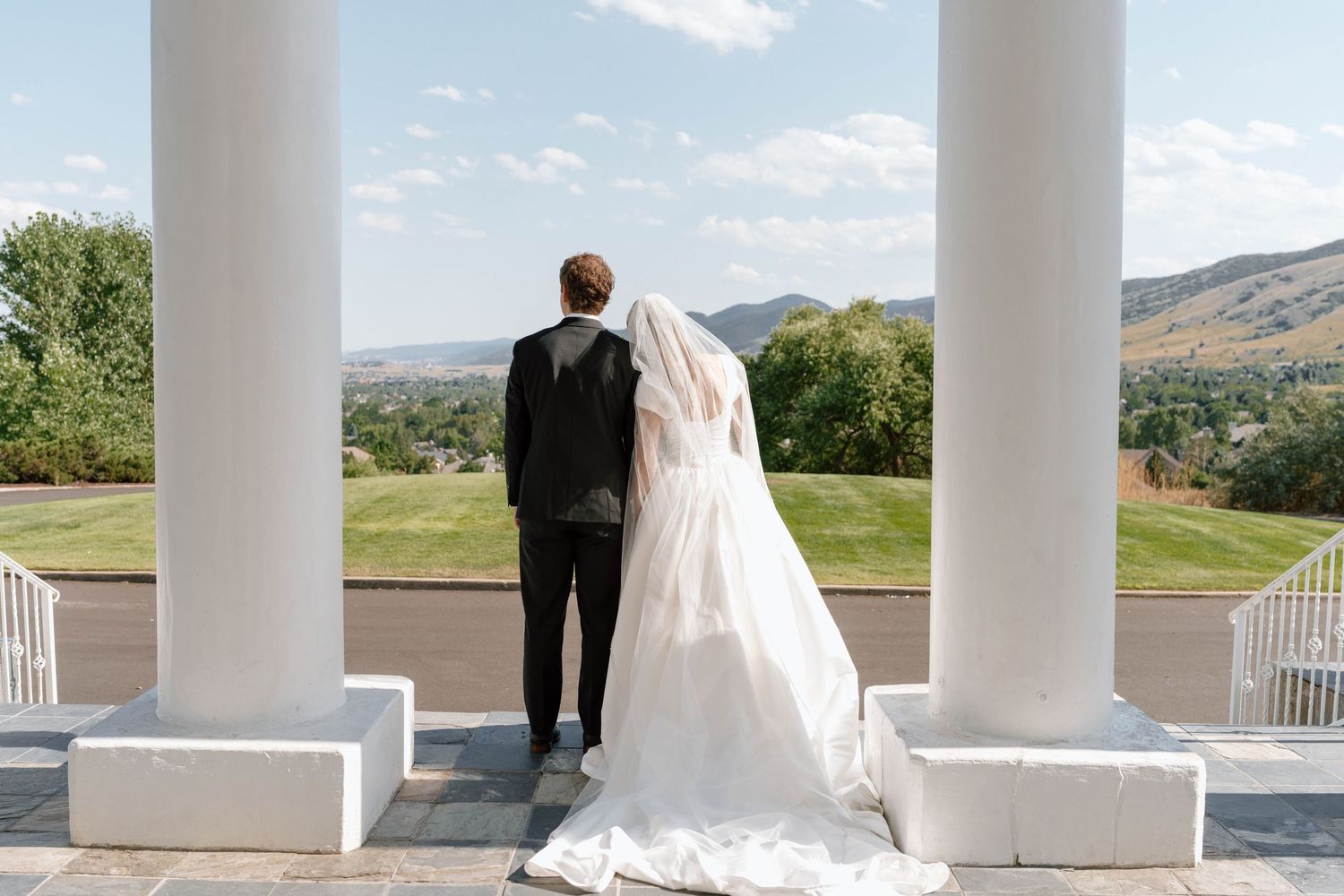 Elegant white columned porch overlooking mountain landscape on a sunny day.