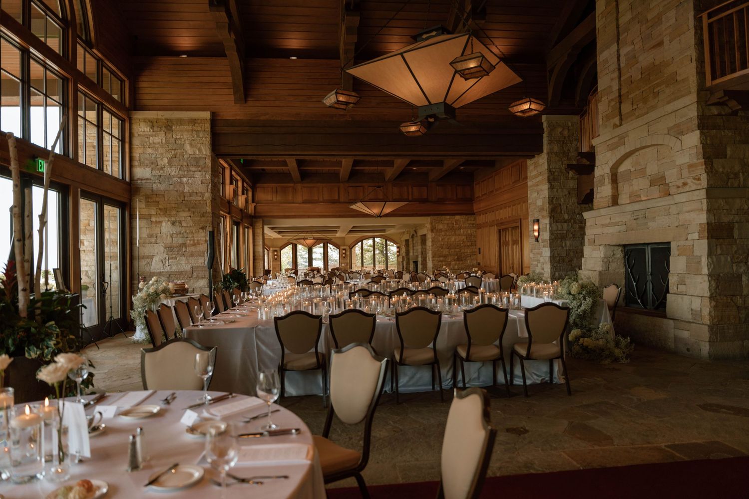 A panoramic view of a rustic stone wedding reception venue with wooden beams and elegant table settings.