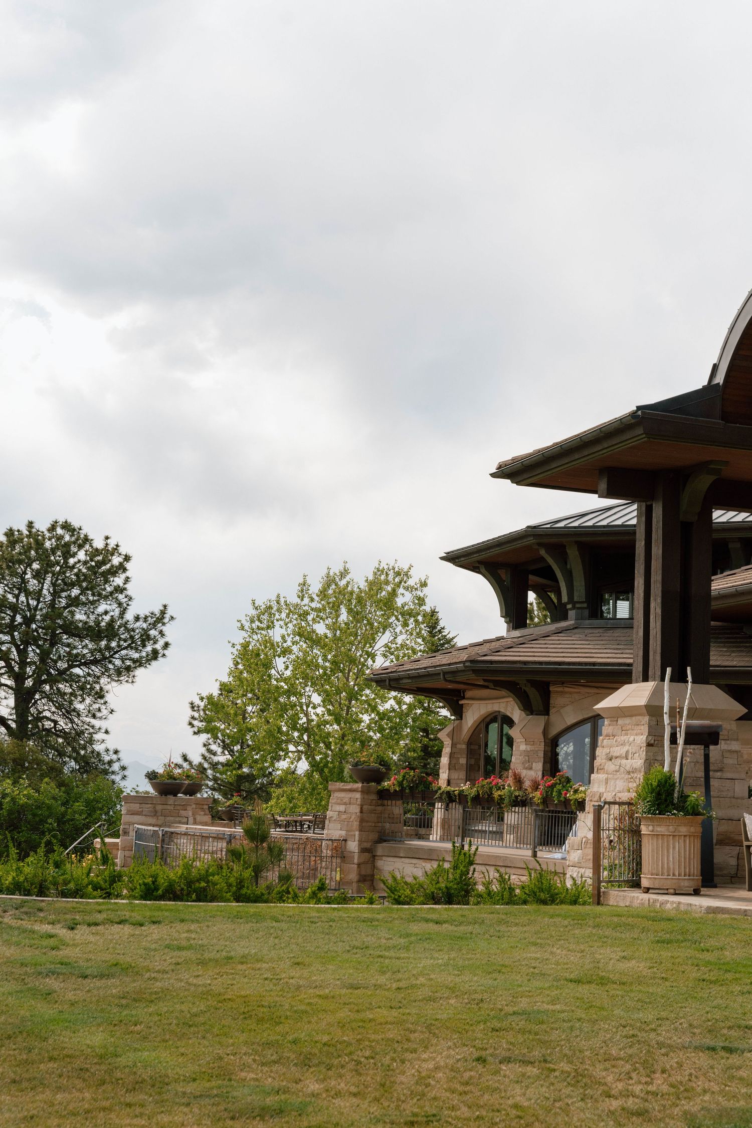 Stone and wood architectural entrance to an upscale golf club or resort with landscaped grounds.