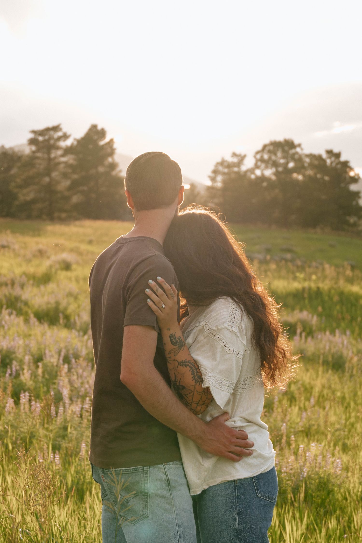 Romantic couple embracing in a wildflower field during golden hour.