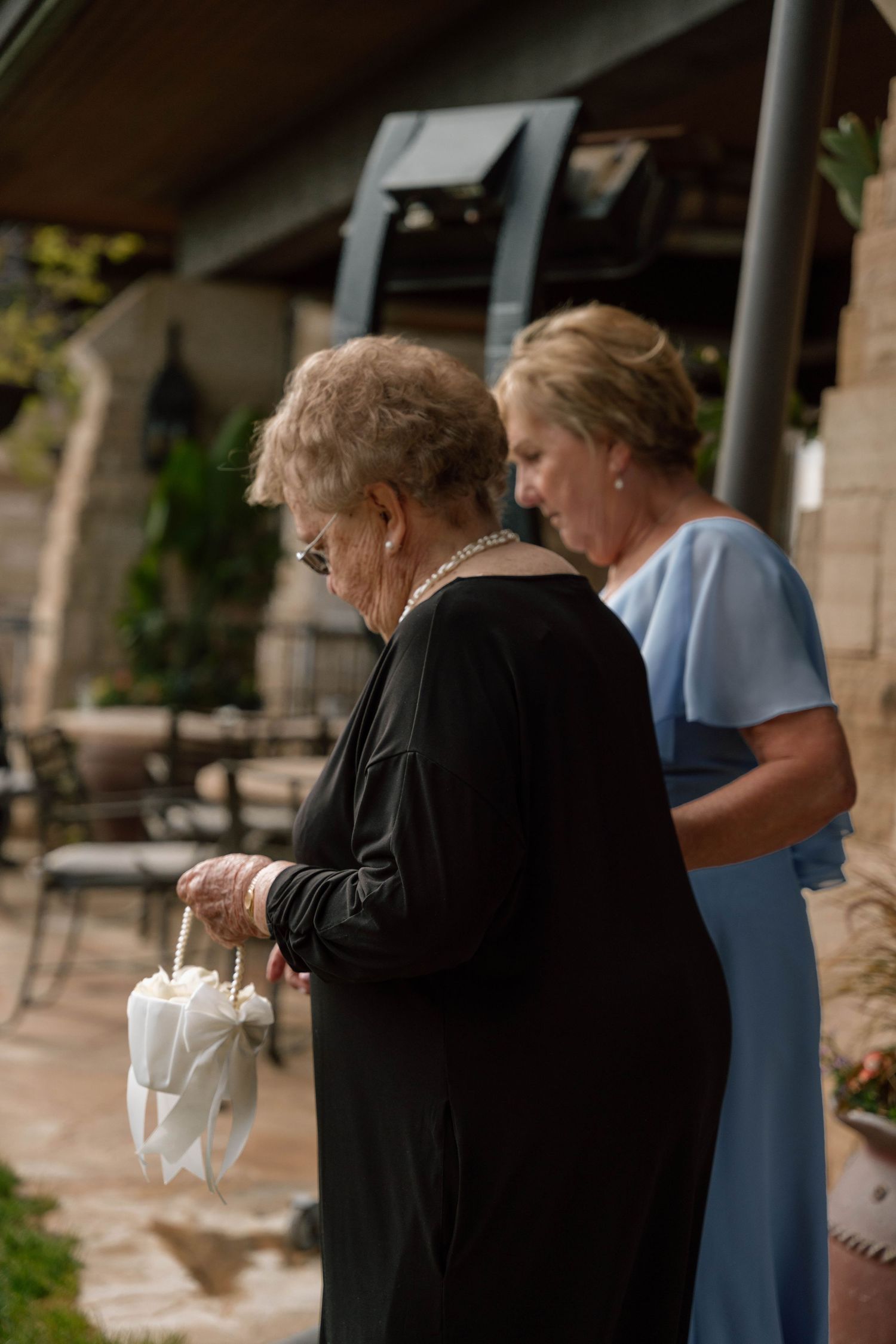 Wedding guests mingling under a covered stone patio during reception.