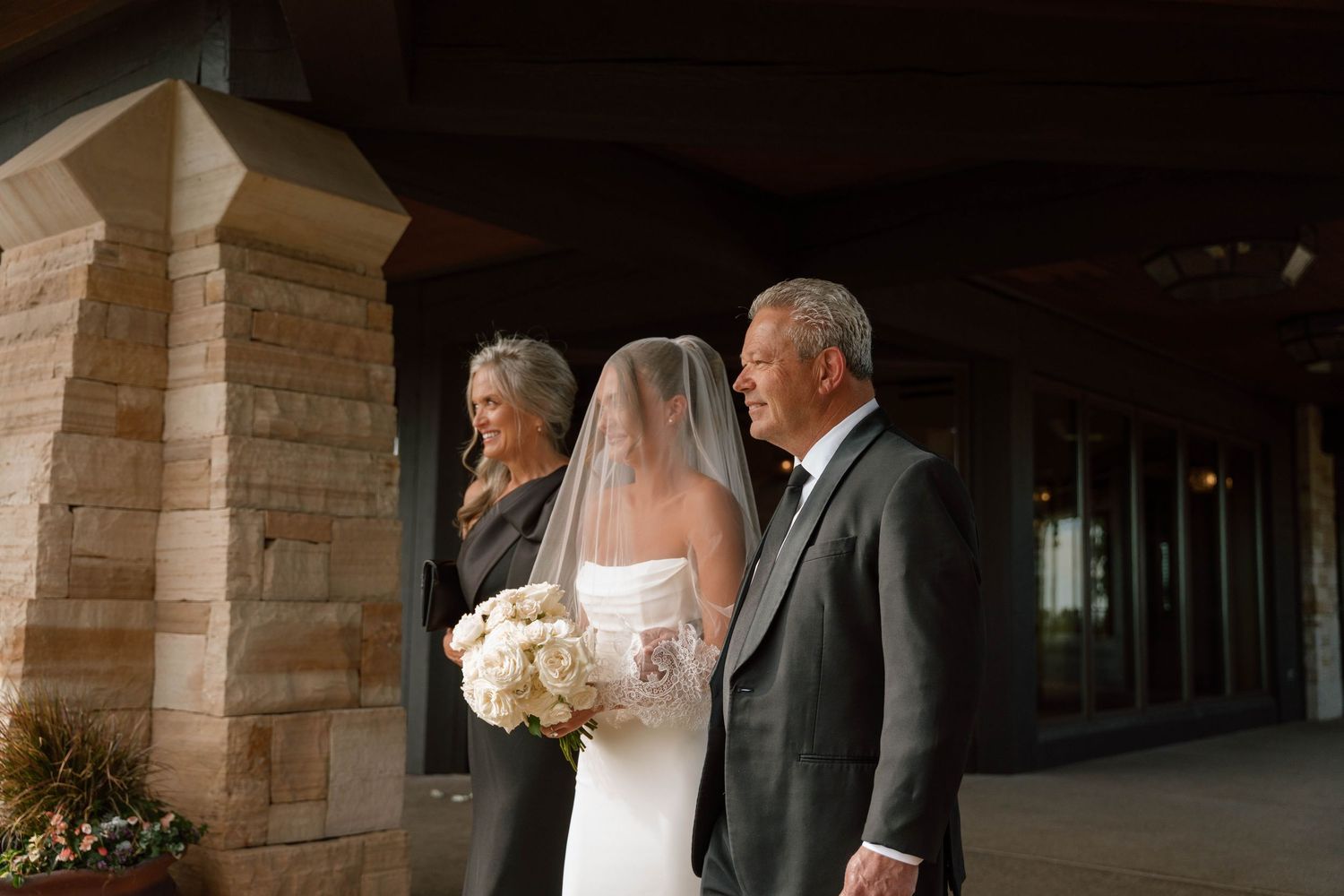 Wedding party members walking through an elegant covered stone passageway.