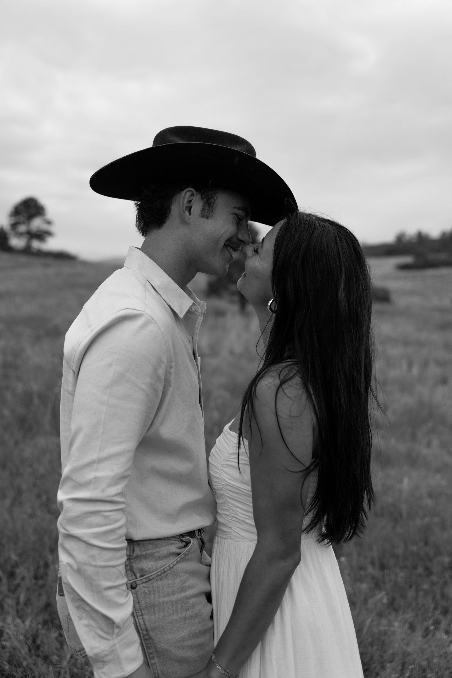 A black and white portrait of an intimate moment shared in a rustic field setting.
