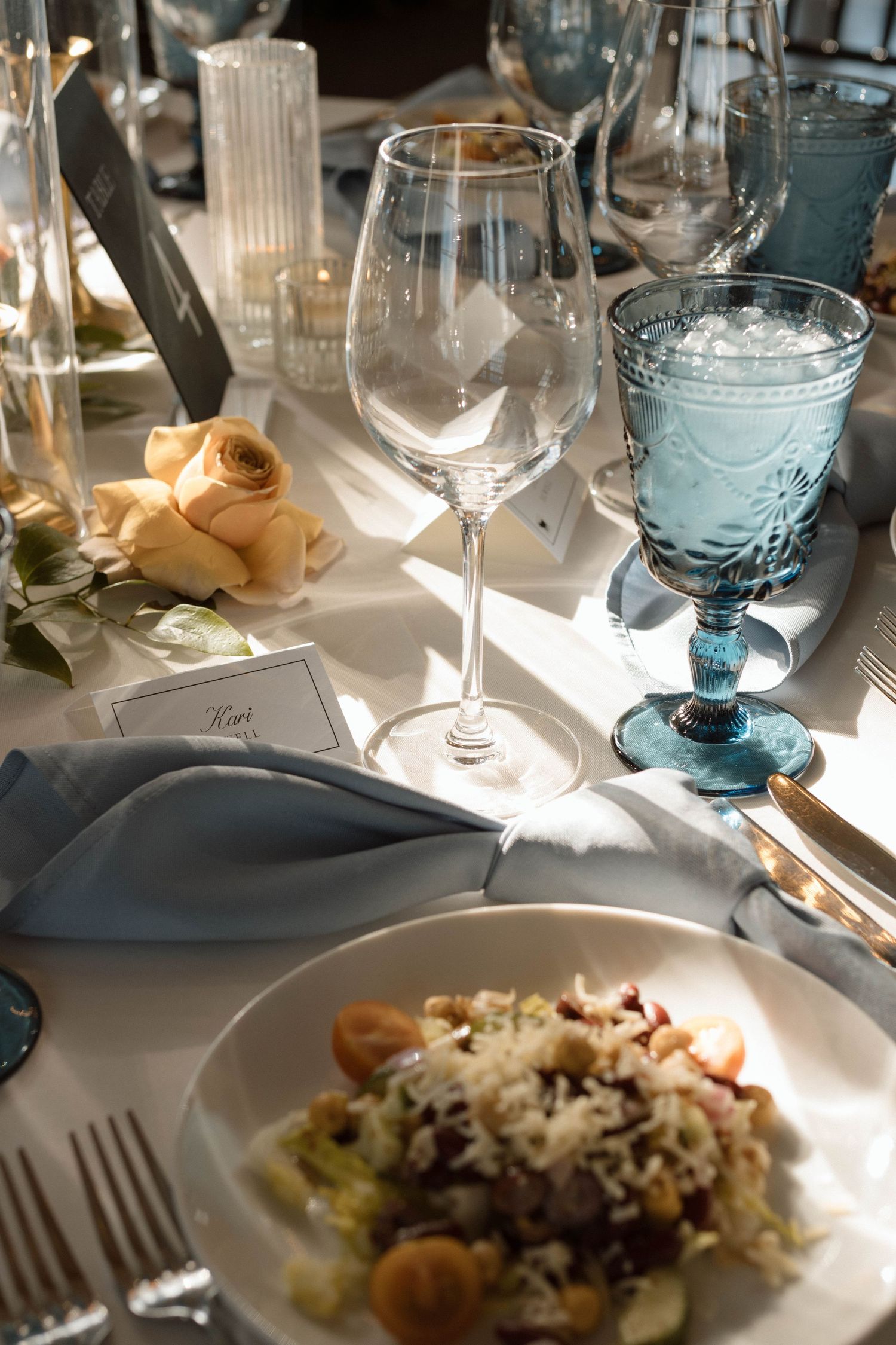 An elegant table setting with blue glassware and plated meals at a formal event.